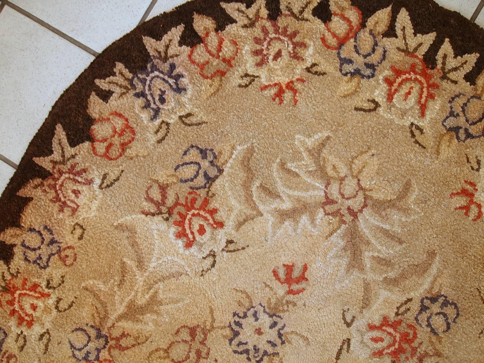 Handmade antique American hooked rug in original condition. The rug is in light pastel shades of brown, beige and red. The rug is in beautiful floral design and has oval shape. The condition is original and good.