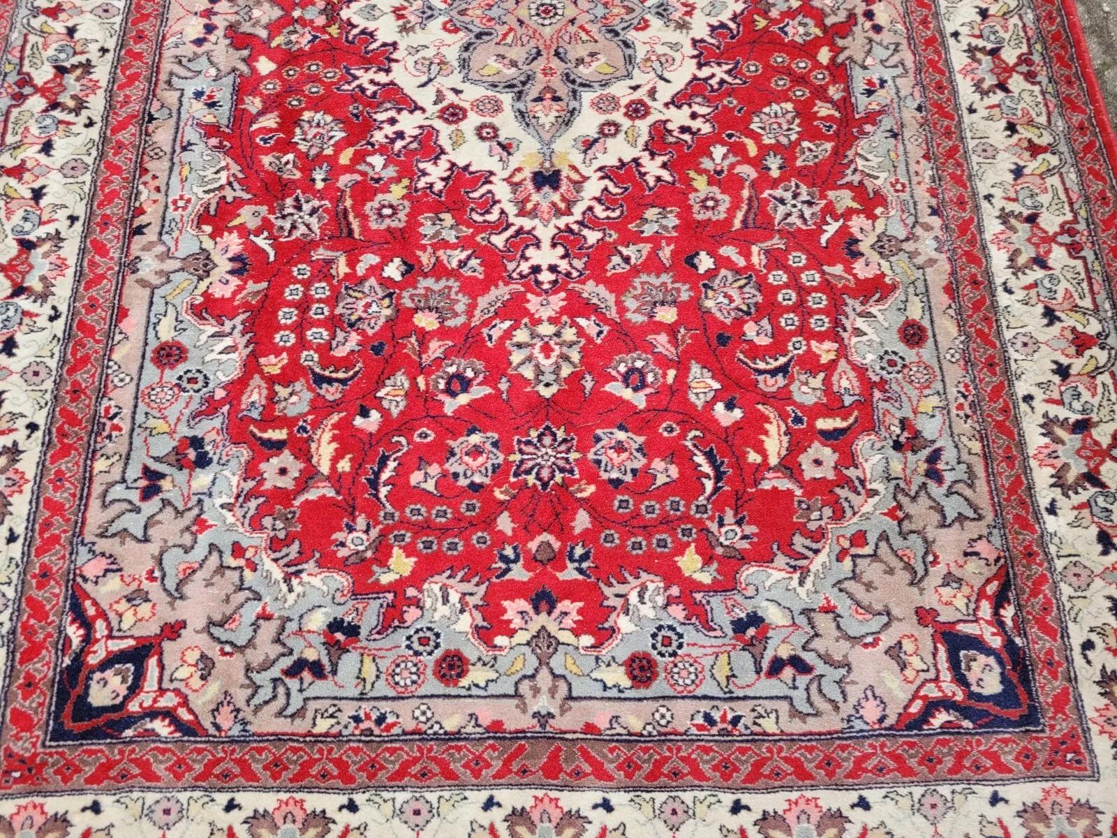 Questo straordinario tappeto persiano Sarouk vintage mostra una miscela senza tempo di eleganza e maestria. Realizzato a mano a metà del XX secolo, questo tappeto in lana presenta un ricco campo rosso cremisi centrato da un medaglione avorio