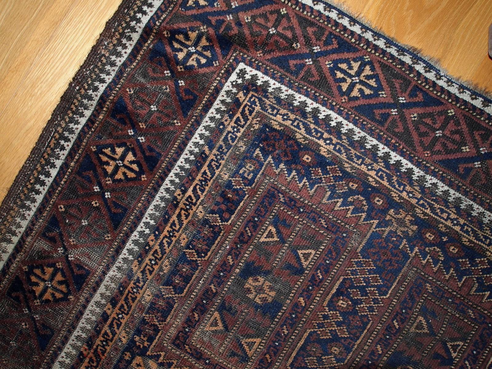 Antique handmade Afghan Baluch rug. This rug has tribal design in brown, burgundy and blue shades. Condition is worn due to age, but still very beautiful rug. Also very unusual size for this type of rugs which makes it an interesting piece of art.