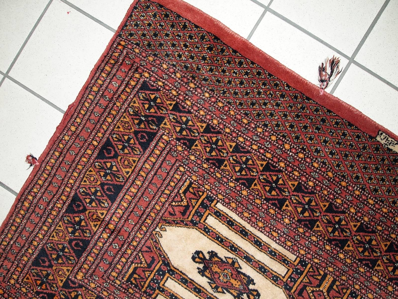 Handmade semi-antique Turkoman rug with beige field and red border. Orange color accented on tribal figures. The pile on this rug is thick, soft and comfortable. Great little piece could warm up and beautifully decorate any small space in the