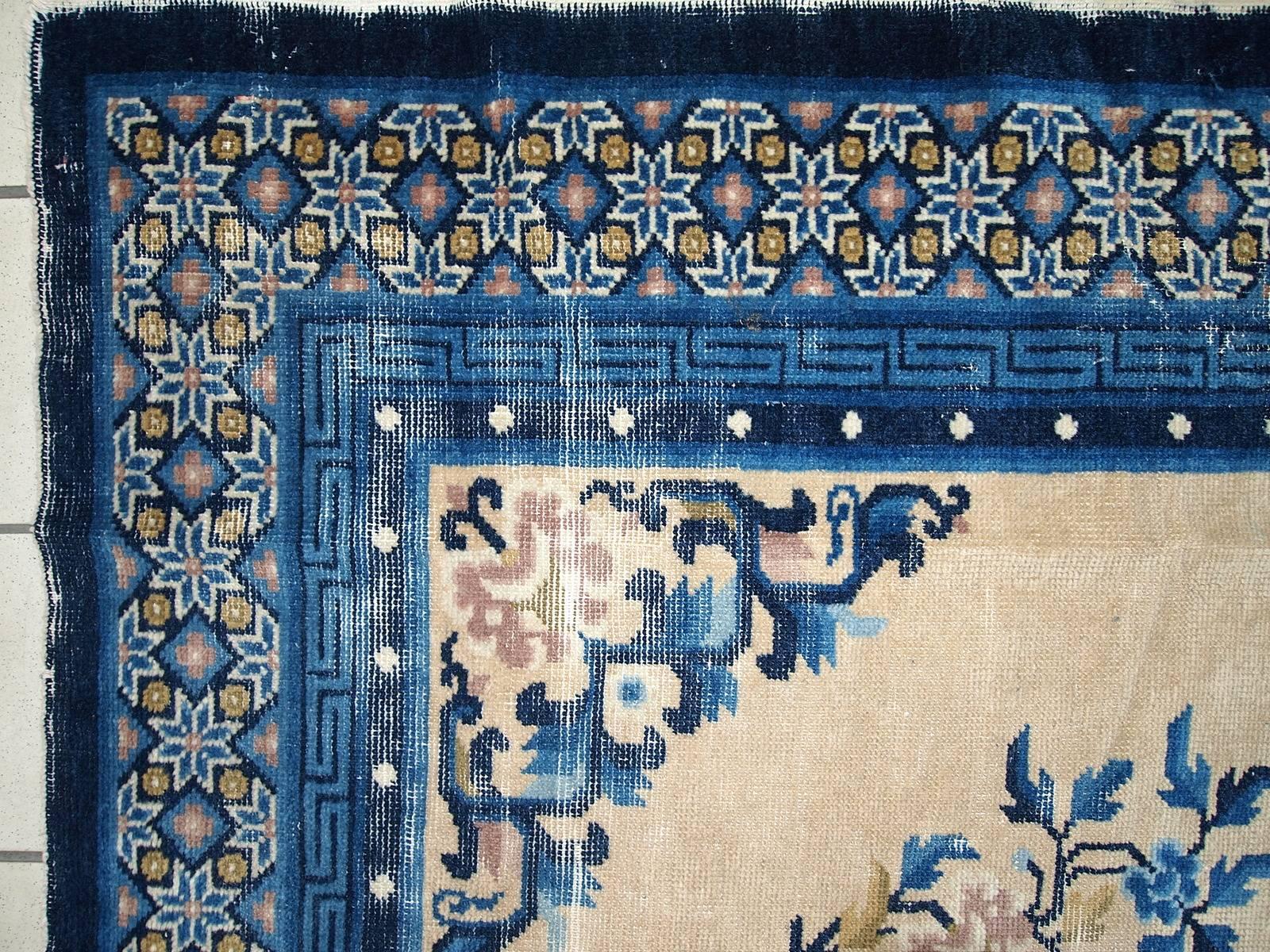 Antique Peking Chinese rug in original condition. The rug is typical looking Peking design. Very thin made with high quality wool. Beige background with a blue border and classic design. Beautiful medallion in the centre and little flowers and