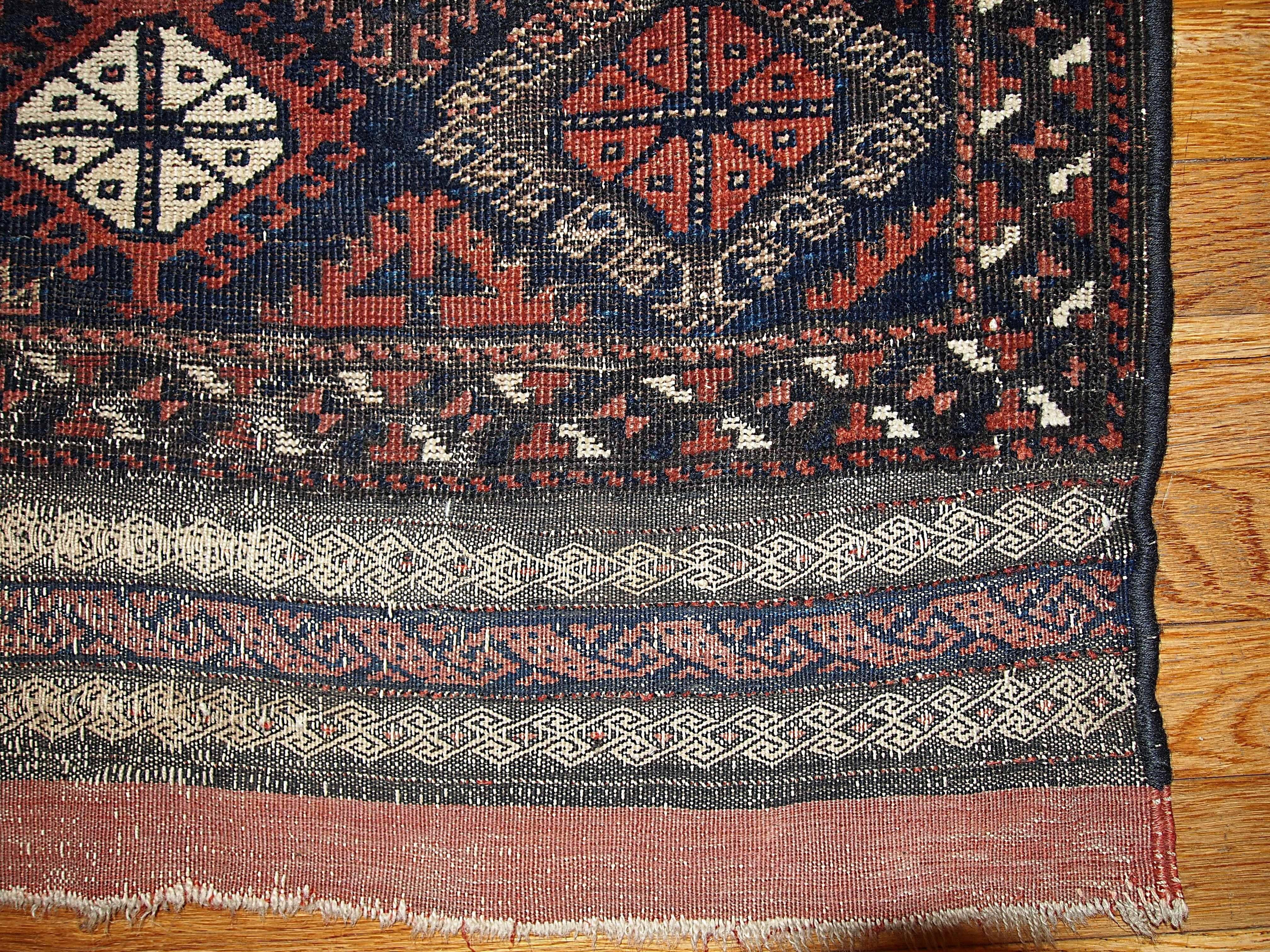 Handmade antique collectible Afghan Baluch rug in unusual design. Tribal pattern in deep burgundy color with geometric looking border in beige and red shades.
 