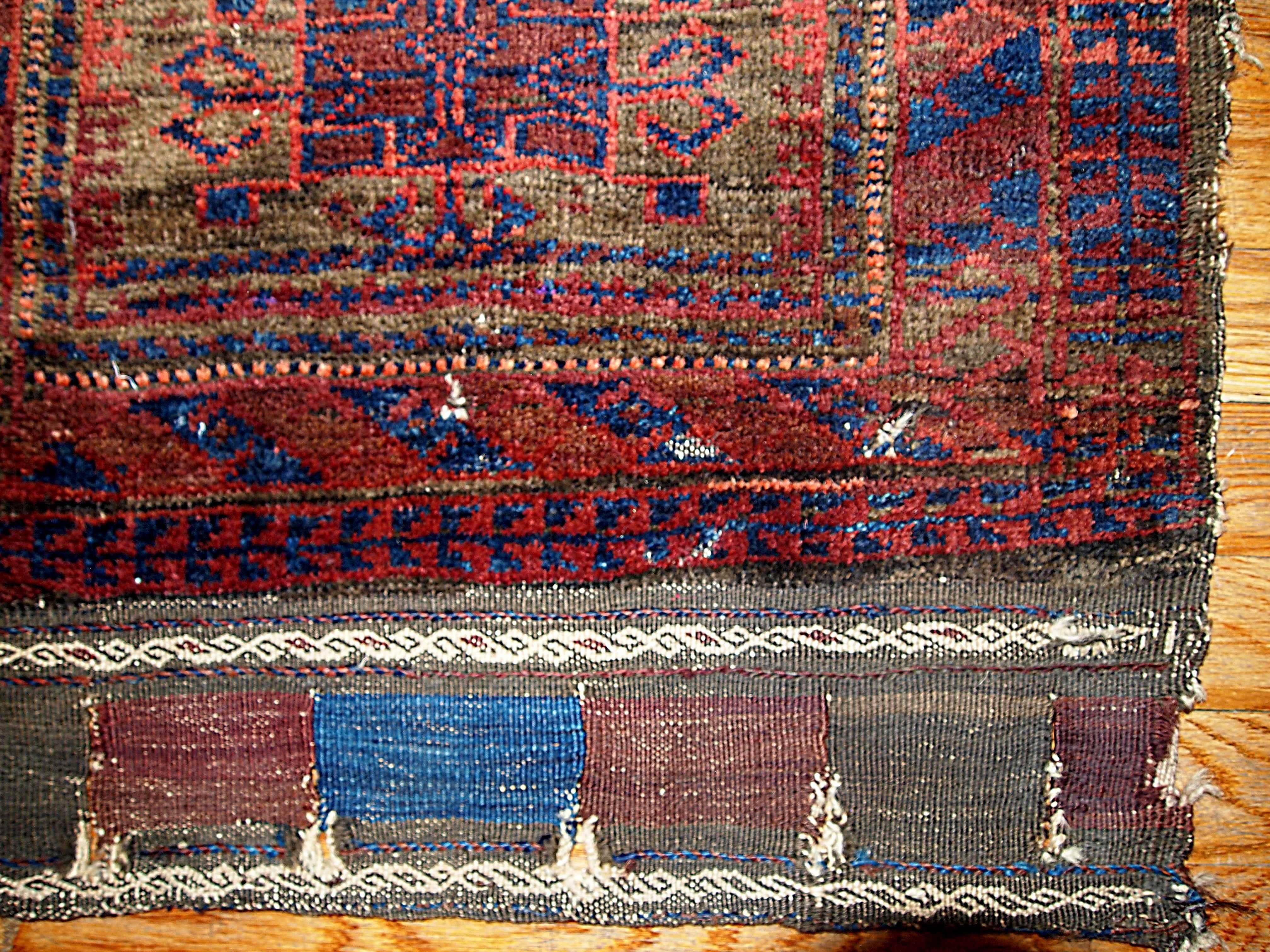 Square antique collectible Afghan Baluch bag face. The beautiful background color mixed in brown, burgundy and red with a shiny blue design all around it throws us in the magical tribal atmosphere of 19th century in Afghanistan.