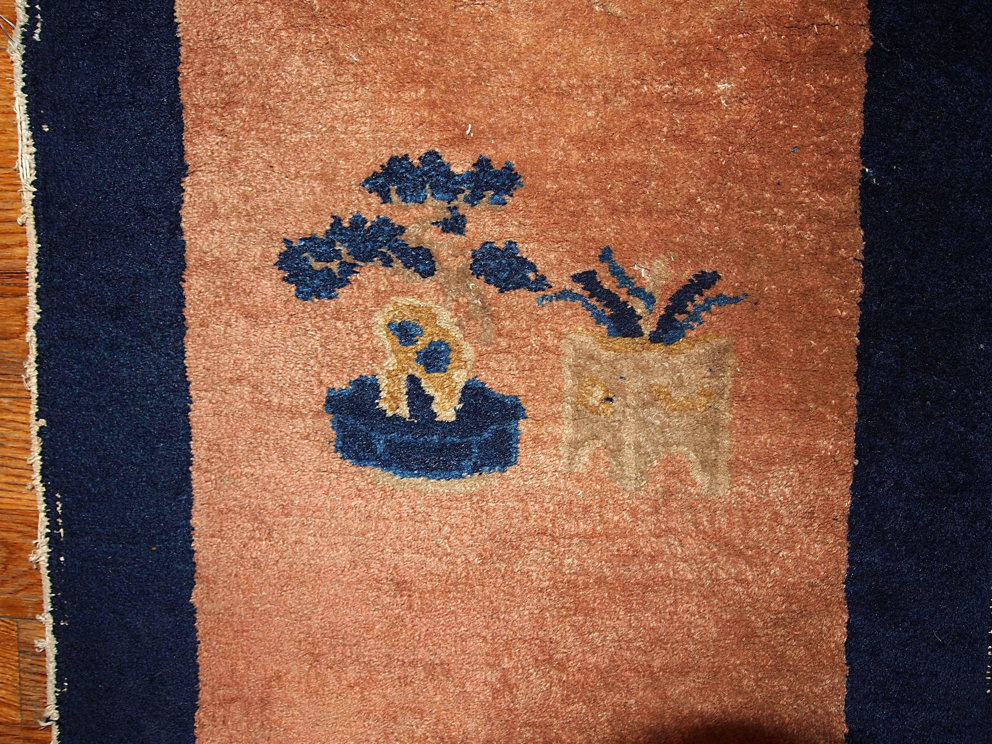Crafted in beginning of 20th century this Peking Chinese rug represents the fashion of minimalism which was popular on that time. Nice peach colored field and navy blue border with an image of tree in the center.