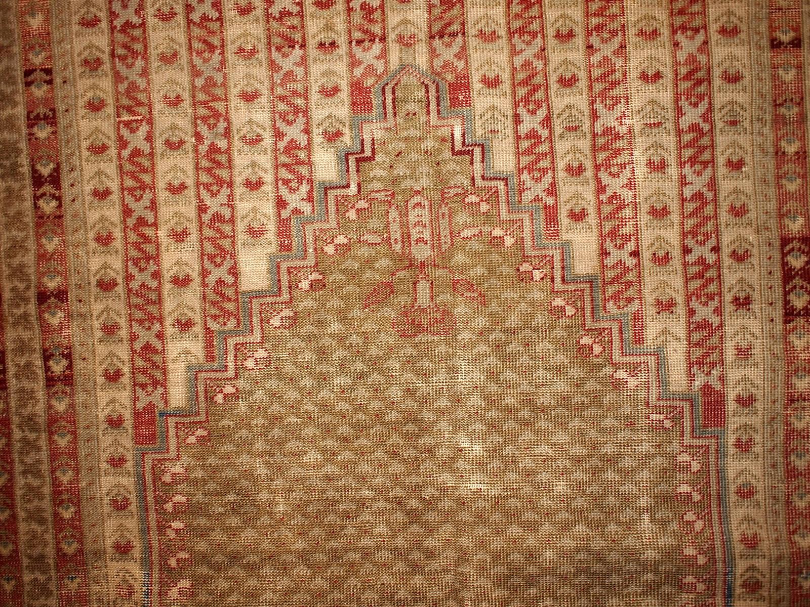 Antique collectible prayer Turkish Ghurdes rug. The rug is damaged by age and condition is not perfect, but still the pattern and colors are gorgeous on it. The rug is in olive green color and lots of little borders in burgundy, red and beige shades