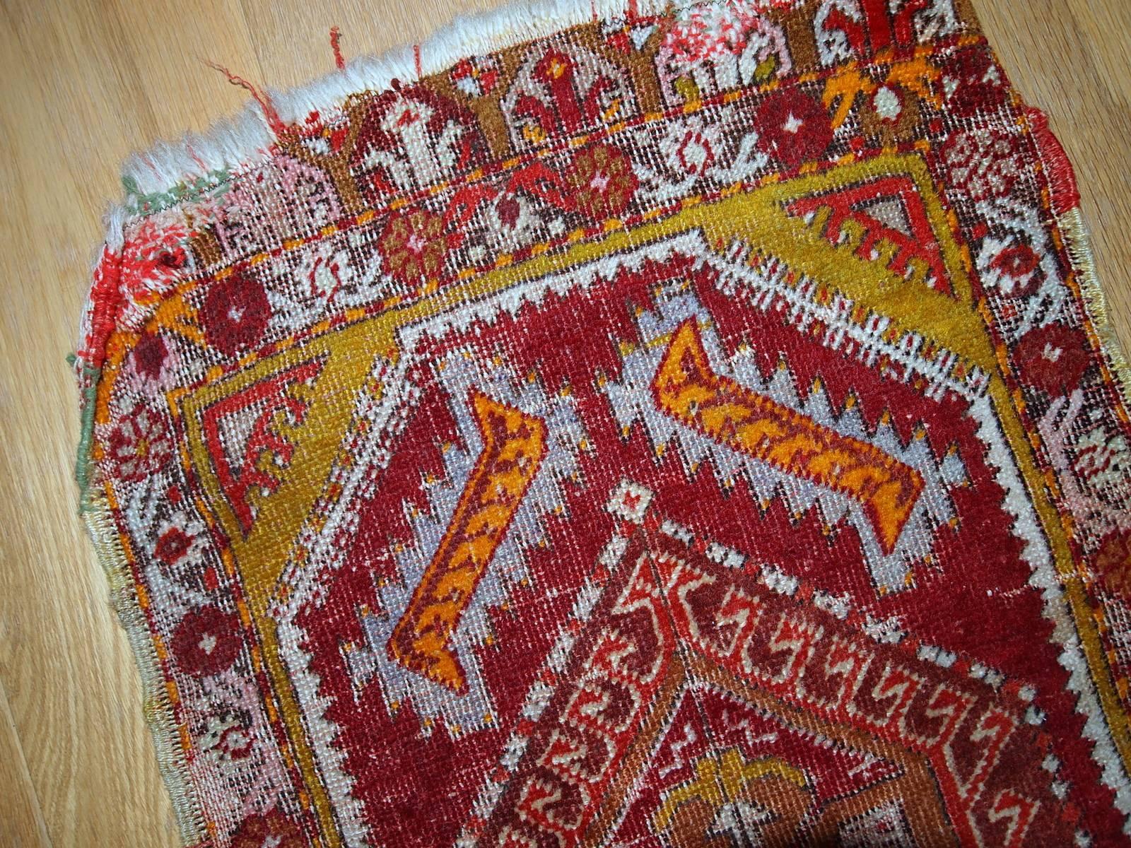 Antique Turkish Yastik rug in original condition. The rug was made in traditional design for its type in bright red colour with some accents of gold, orange and olive brown shades. Condition of this rug is warn by the age.
 
