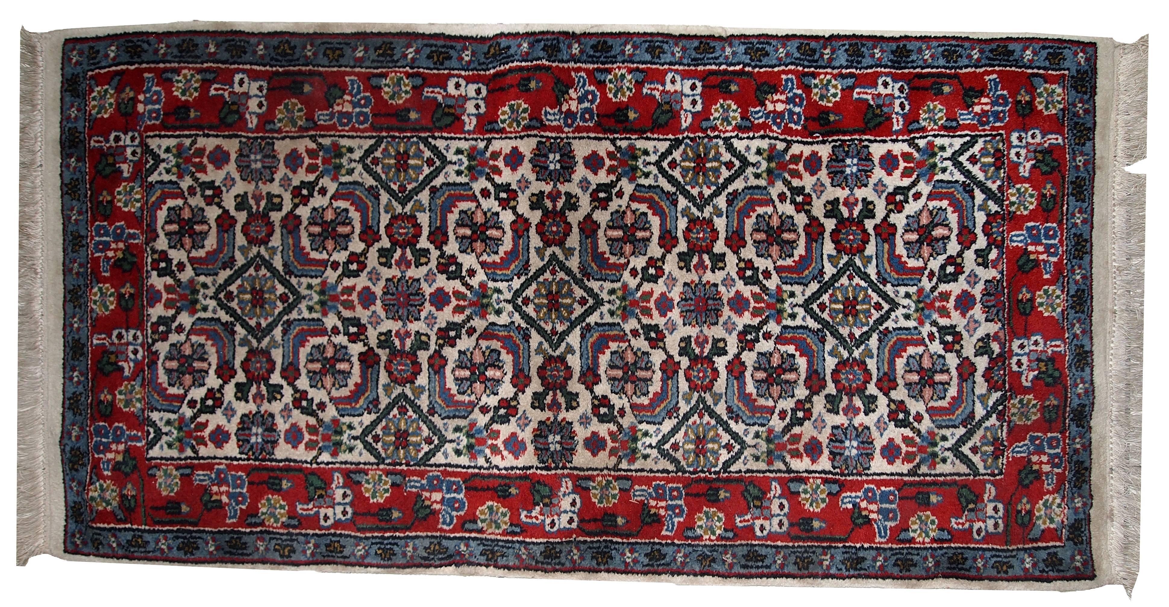 Vintage Indian Agra rug in original condition. The white background of this rug contains chaotic and repeating in the same time geometric design. The red border following turquoise surrounding the background. Nice combination of colors and very