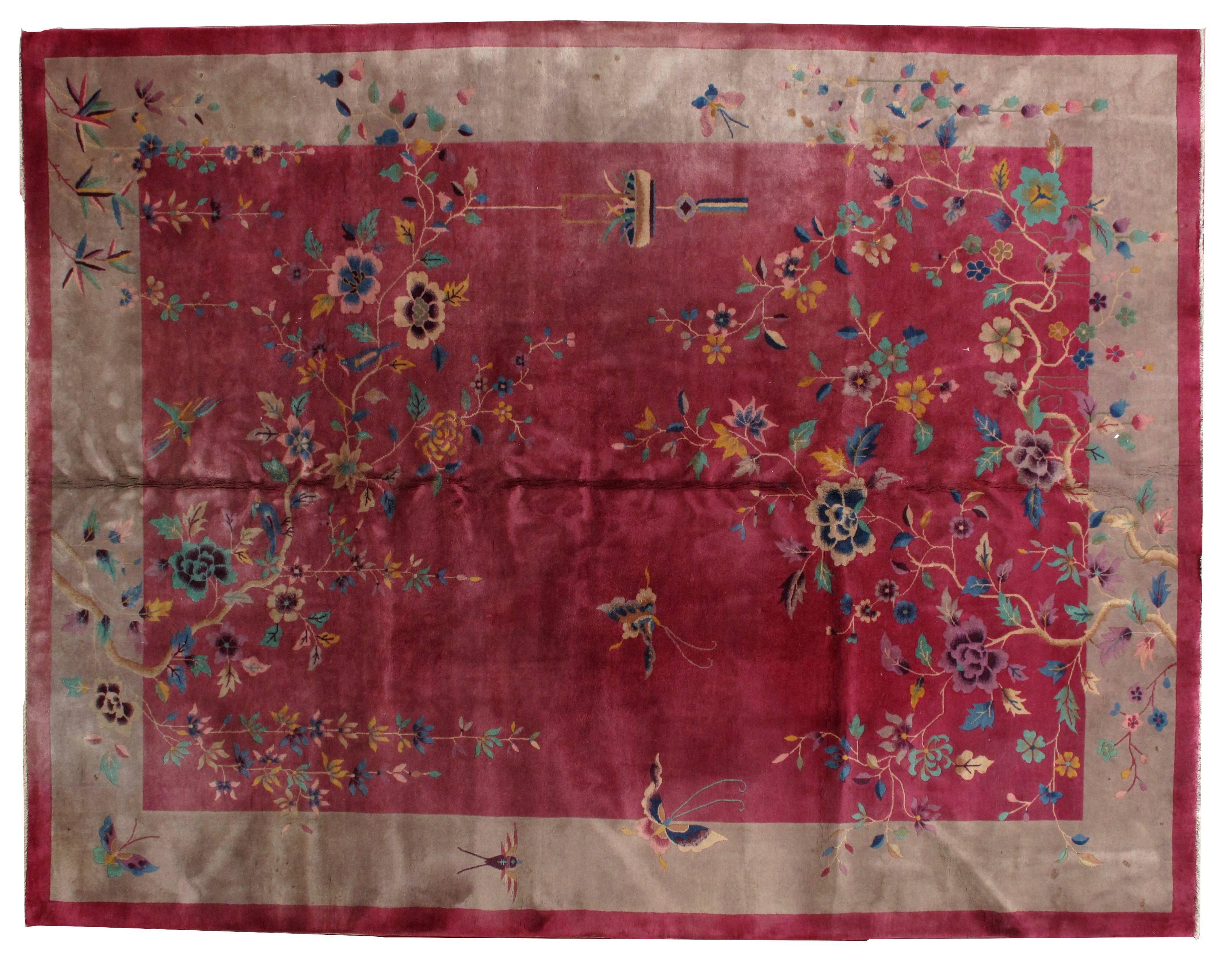 Antique Art Deco Chinese rug in original condition. The rug is made in fuchsia color with cream beige border. Beautiful Art Deco design decorating the rug with the branches full of large colorful flowers and butterflies. The rug is in original good