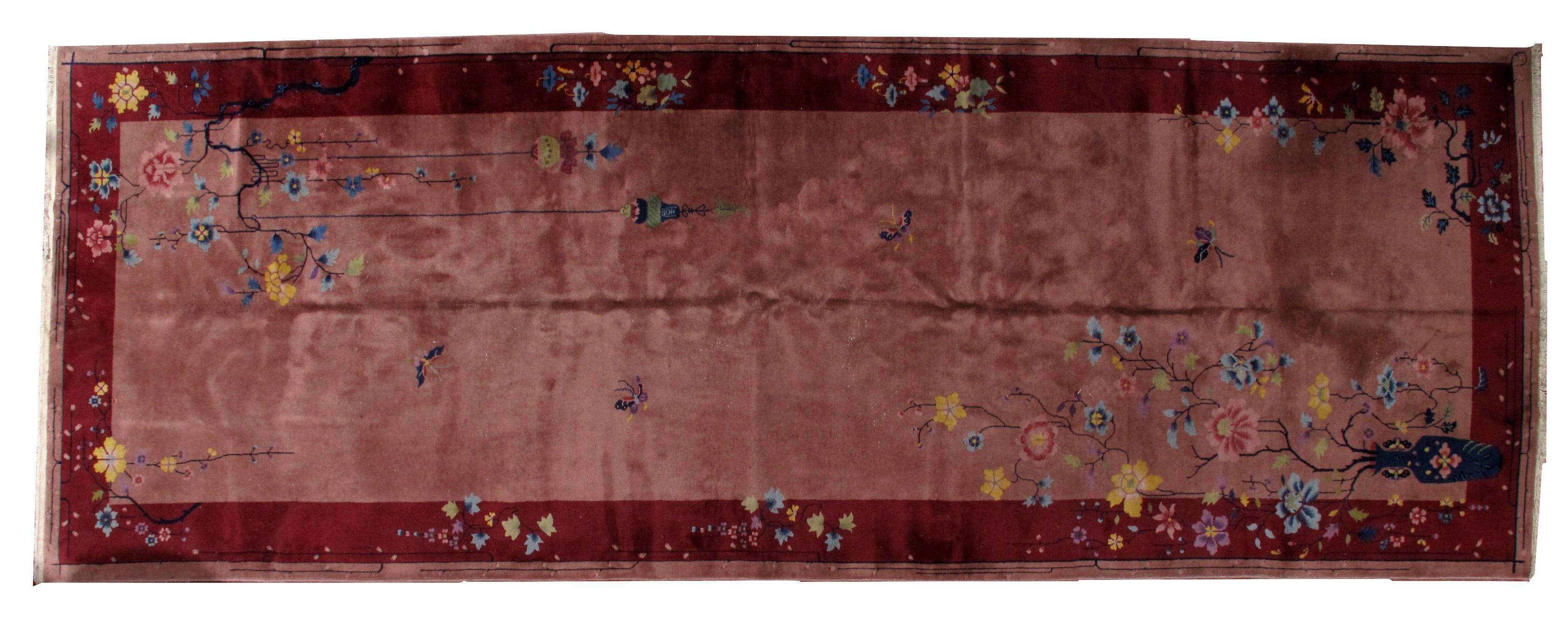 Antique Art Deco Chinese rug in original condition. The rug is in burgundy color with darker burgundy border. It is decorated with classical Art Deco style: vase, branches with the flowers and leaves. The colors on this rug are combined very well