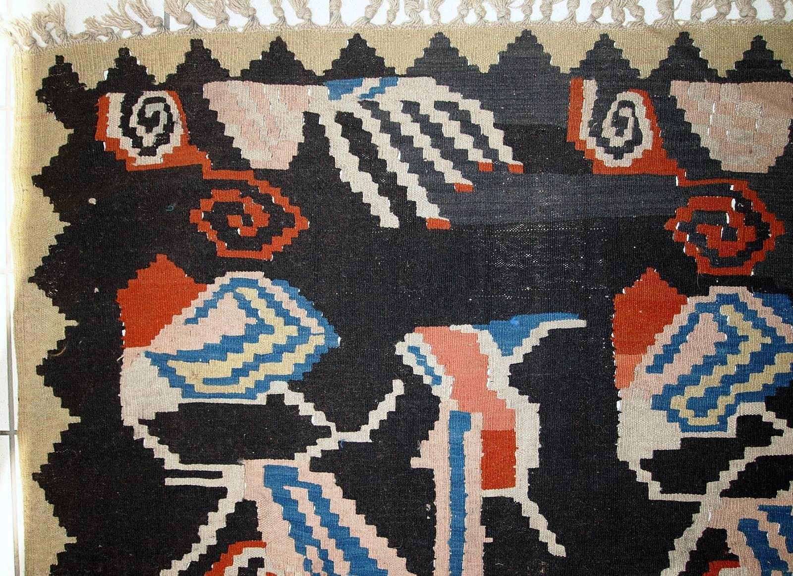 Antique handmade Caucasian Karabagh kilim in original condition. This kilim has been made in black colour and large colourful abstract images are decorating it. The border made in beige shade in triangle shape. It is in original good condition with