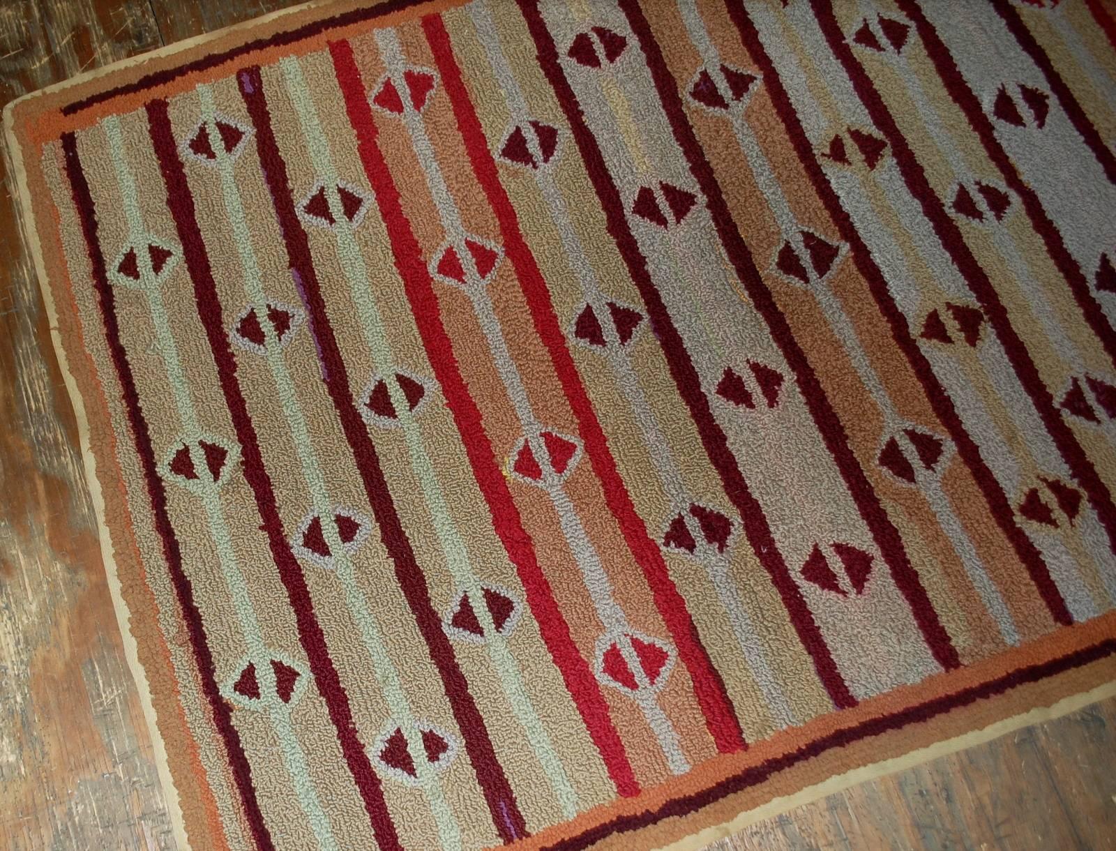 Handmade antique American hooked rug in good condition. The rug has been made in geometric design. Repeating diamond shaped pattern on colourful stripes all over the rug. Very thin burgundy border surrounding the rug. The rug is in original good