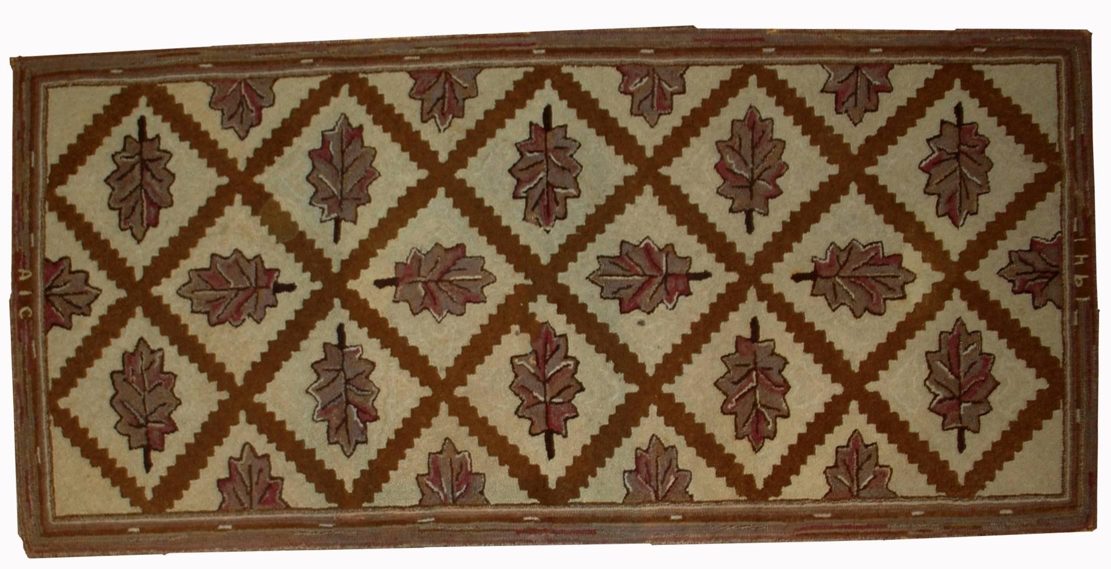 Handmade antique American hooked rug in good condition. The rug has been made in geometric design with diamond shaped figures and leaves inside them. Main colours are beige and brown. The rug has been restored and in good condition now.
     
