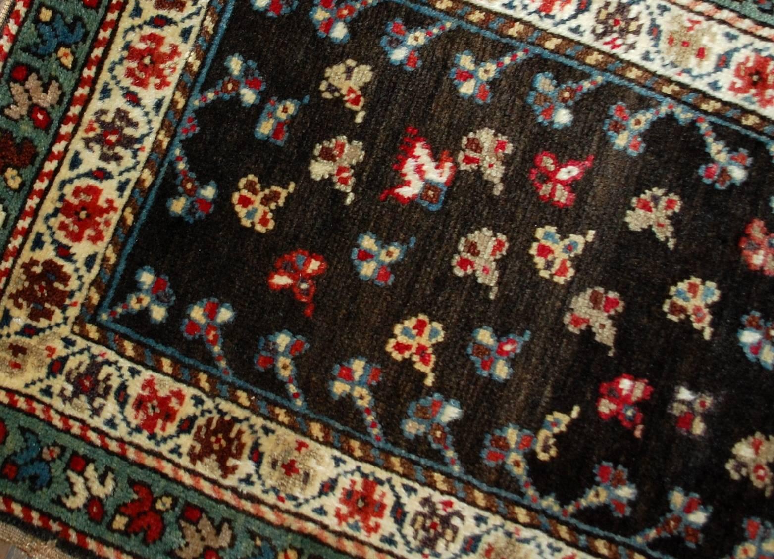 Antique handmade Caucasian Gendje rug in good condition. The rug has beautiful chocolate brown background covered in colorful flowers. Two borders are surrounding the central area: beige and azure. The rug has been restored and now in good