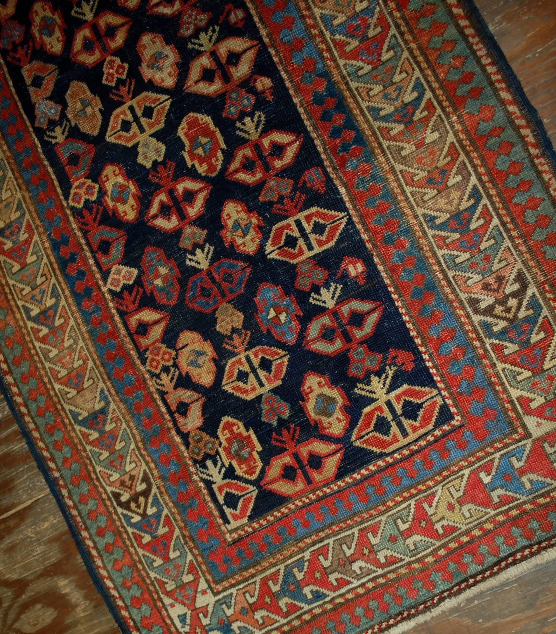 Ancien tapis caucasien Gendje fait à la main et en bon état. Le tapis présente un champ bleu foncé couvert de figures tribales. Il est entouré de la bordure beige. Le tapis a été restauré et est maintenant en bon état.
 