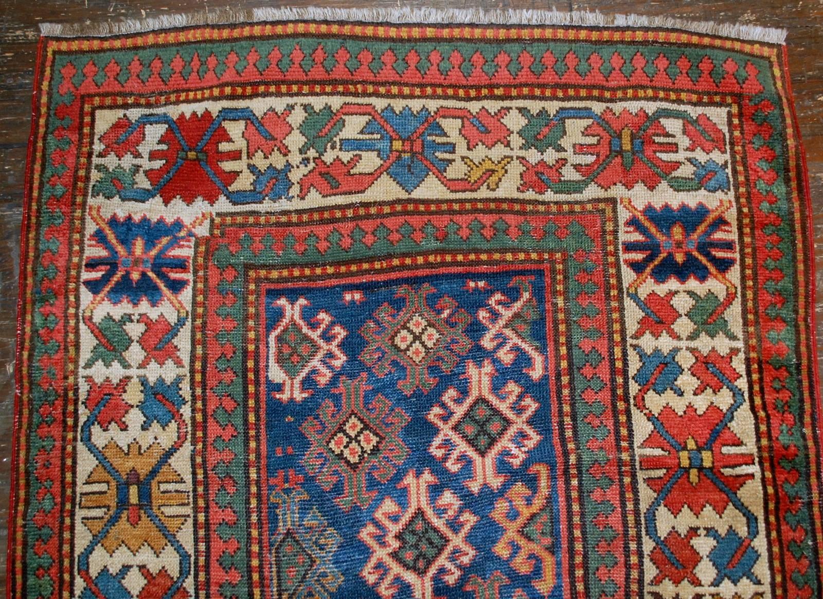 Antique handmade Caucasian Gendje rug in good condition. The rug has dark blue field covered in tribal figures. It is surrounded by the white border with tribal design on it as well. It is has all-over field. The rug has been restored and in good