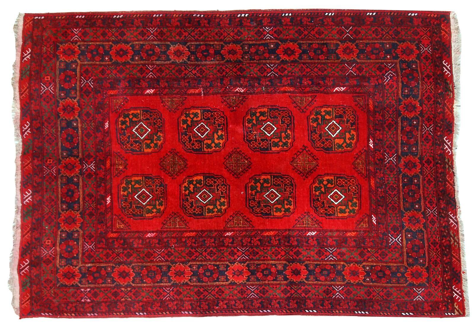 Vintage Afghan Ersari rug in original good condition. The colors on this rug are very bright. Extremely bright red in the center decorated in symmetric ornament. The very beautiful border contains several thin borders in different design: floral and