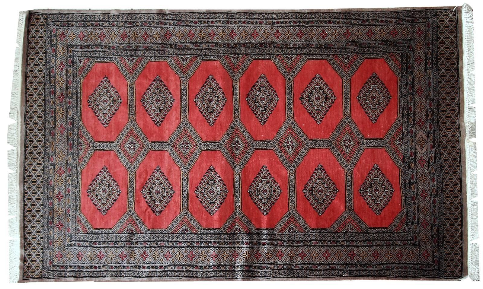 Vintage handmade Uzbek Bukhara rug in original condition. The rug made in classic Bukhara design. Bright red background decorated repeating ornaments and surrounded by a grey (light burgundy shade) border with very precise detailed design. The rug