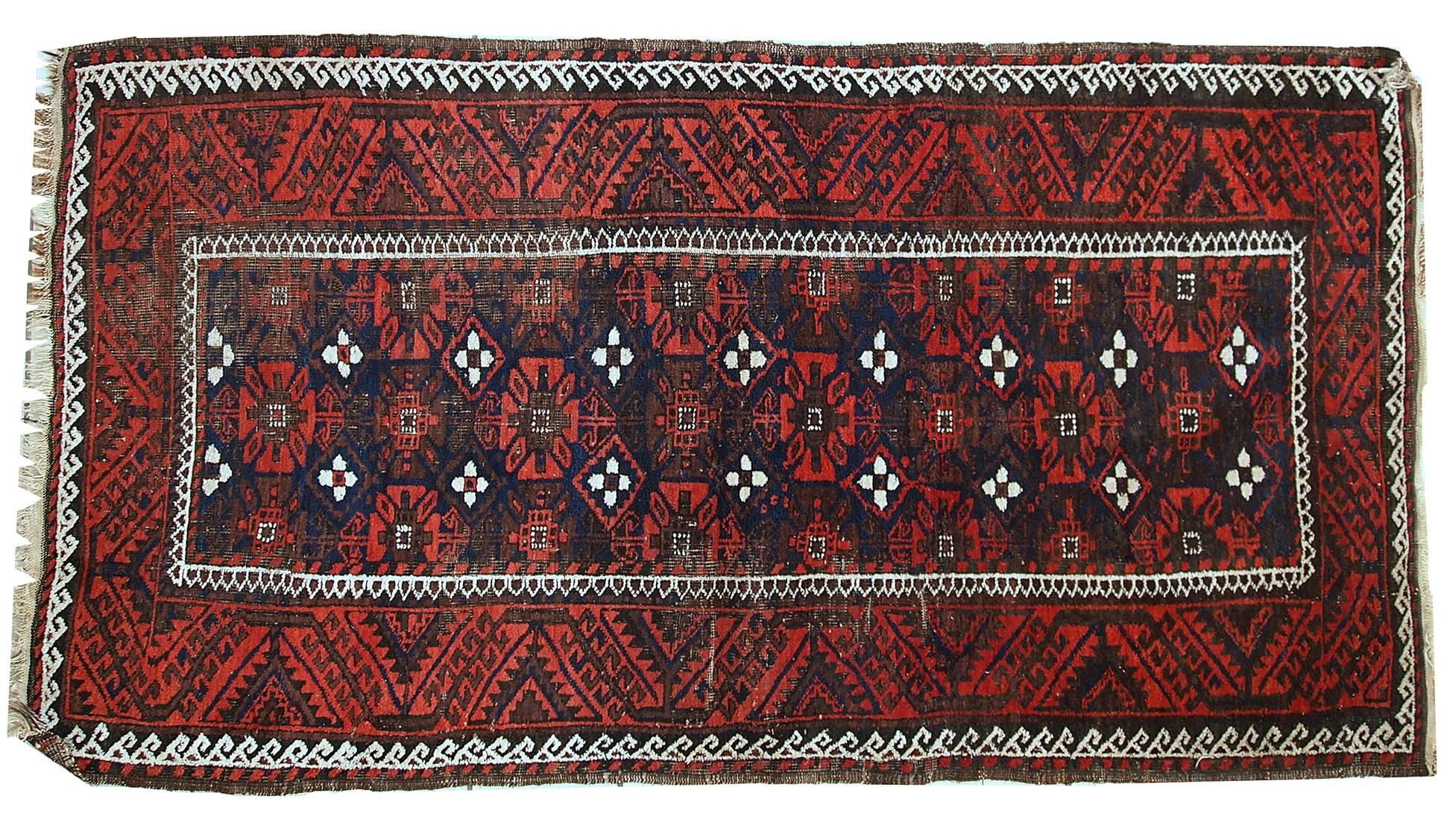 Antique handmade Baluch rug in deep shades of rust, blue and brown. Traditional tribal ornaments are decorating the rug. It is in original condition, has some wear due to age.
 