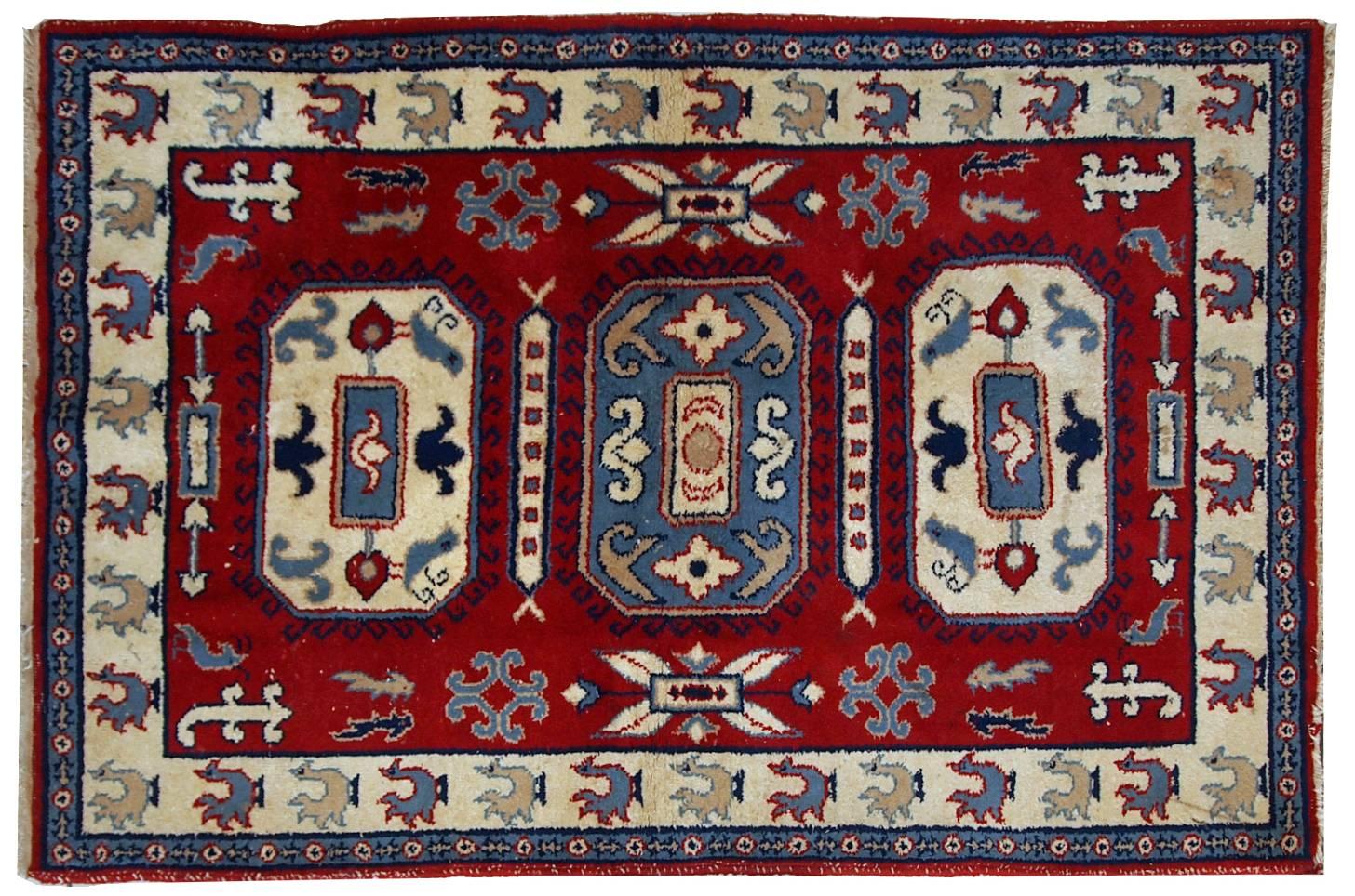Handgefertigter russischer Vintage-Teppich in tiefrotem Farbton. Die beigefarbene Bordüre ist mit Hähnen verziert. Im Allgemeinen ist der Teppich im Tribal-Design gehalten. Der Teppich ist aus Wolle gefertigt und sehr dick und warm. Es befindet sich