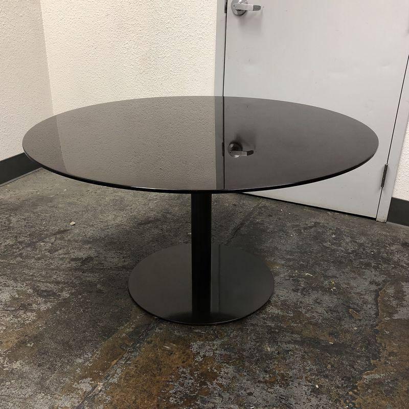A round Bellagio table by Minotti. Designed by Rodolfo Dordoni. The table features an modern and elegant design. A sleek in curved wood veneered in Mud Glossy lacquer finish that rests on a metal support with painted glossy mud glossy finish. This