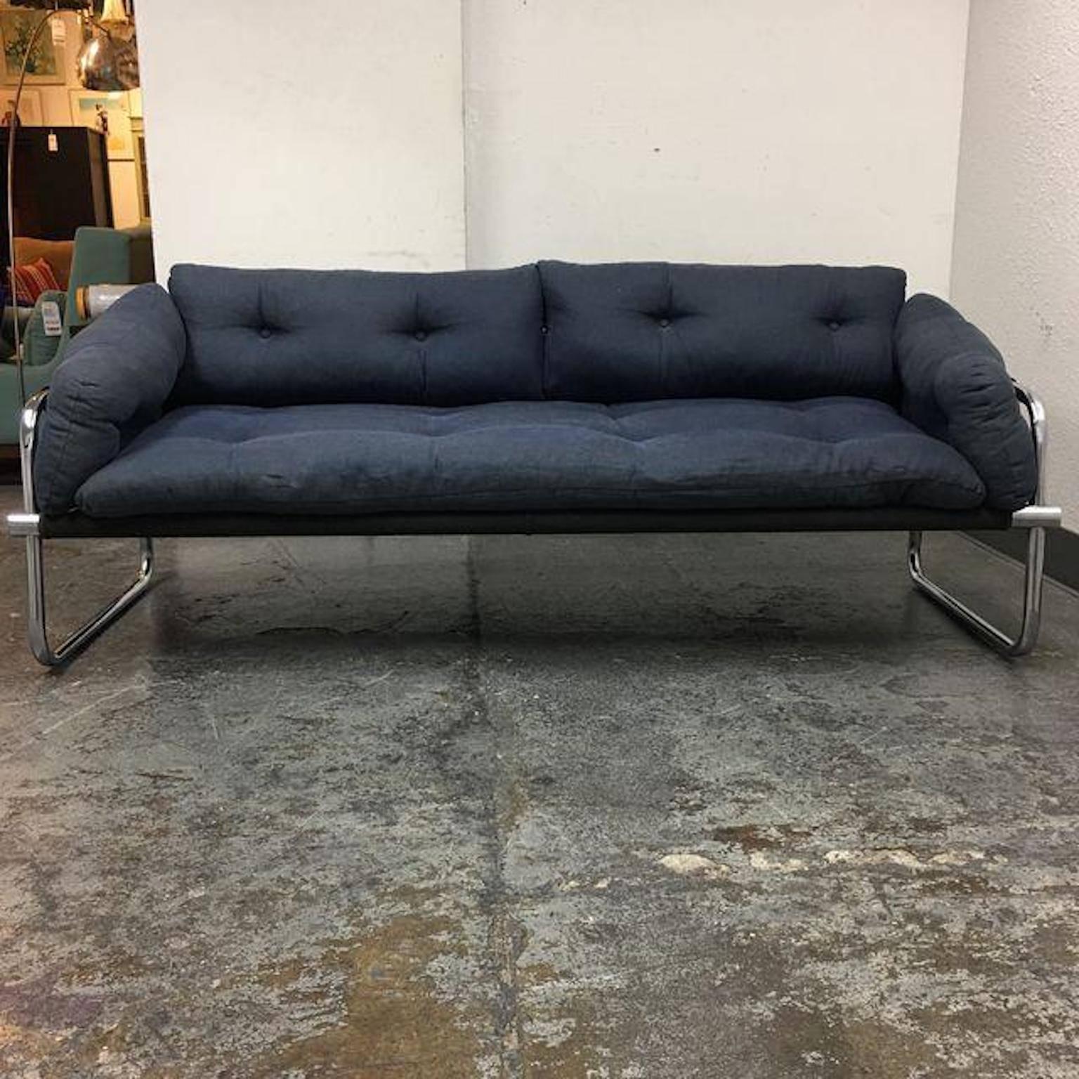 Design Plus Gallery has Landes Manufacturing Company sling sofa designed by Jerry Johnson. The sofa is made from bent chrome tubes fused together. The sling is a black canvas, includes original sets of navy blue linen tufted pillows. Fabric shows