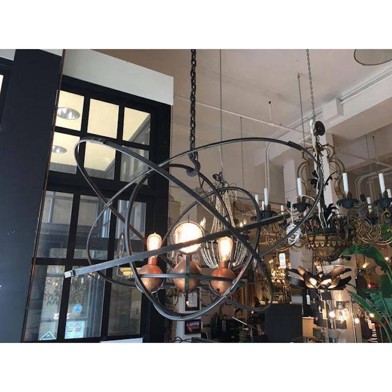 A fascinating chandelier by Jefferson Mack Metalworks. Balanced ellipticals of hand-worked steel surround copper floats and spyglass inspired discs of glass. There are four lights which is design to float among spheres of welded metal. Picture shown