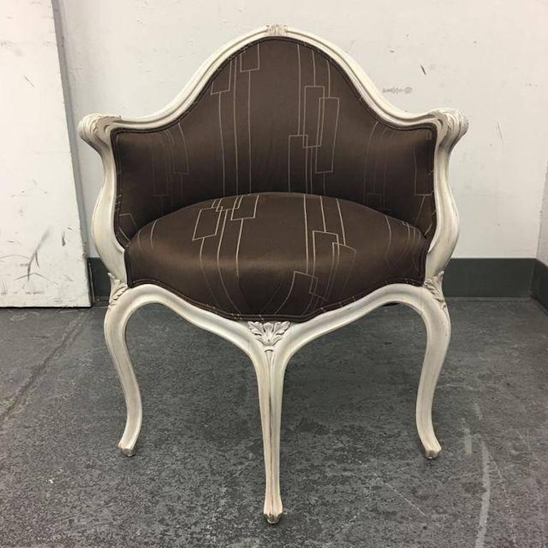 An Art Nouveau corner chair. This graceful little chair has a frame that is beautifully carved and finished in cream finish which has been slightly distressed. The fabric on this chair is a deep rich chocolate brown with a simple geometric