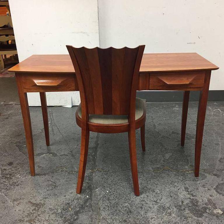 A Aria Desk and Aria chair from Thos. Moser. A grain matched cherry worktable of premium dimension, this table is hand-sculpted from solid blocks of wood. The work surface measures 48" with three drawers. Tapered legs are attached by