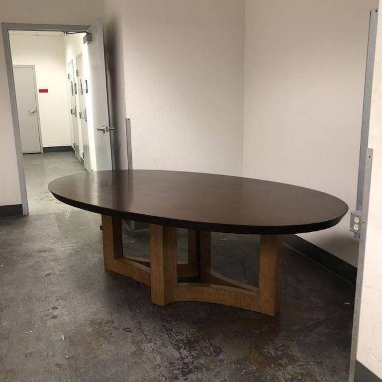 A beautiful dining table by Michael Berman Limited. A oval Mansfield dining table in a espresso finish top with a cirused oak base. The table has one visible scratch and the base has a chip. 

"Michael Berman Limited and Bronze Studio Los