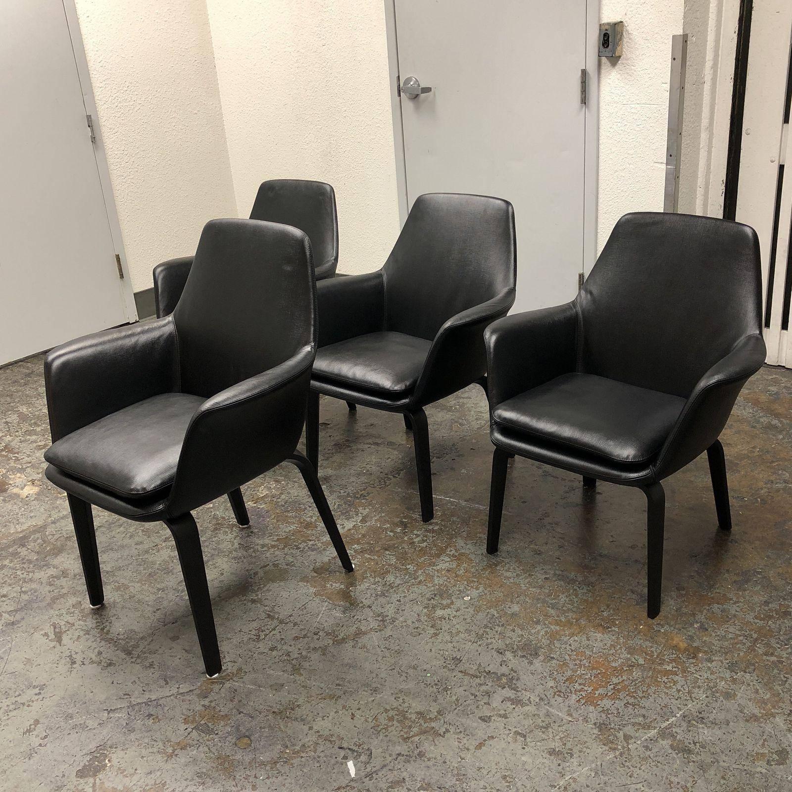 A set of York lounge armchairs by Minotti. Designed by Rodolfo Dordoni. These lovely chairs are to adore. Once armchair is slightly taller then the other three chairs. Upholstered in textured black leather. The wood base is in a black finish. Due to