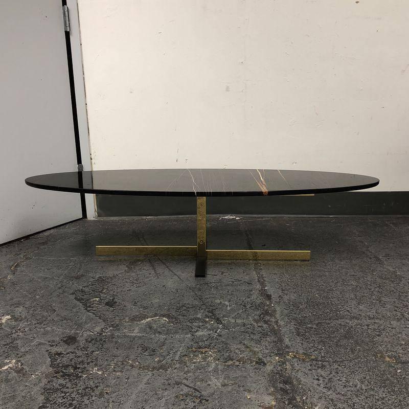 A Minotti Caitlin coffee table. The Caitlin line was designed by Rodolfo Dordoni for Minotti. The elegant metal base features a cross-pattern motif and is finished is bright a gold made of metal, composed of a pair of “C”-shaped legs with bright