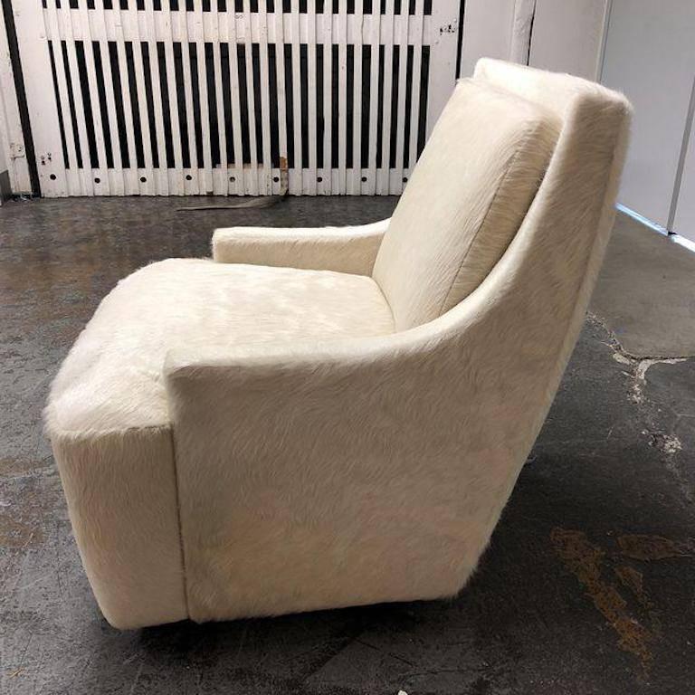 A brand new scoop swivel chair designed by Barbara Barry for HBF. This beautiful chair is upholstered in Edelman of New York Cowhide in White. The chair has no visible feet, so it appears to float two inches off the floor. It has a firm seat and