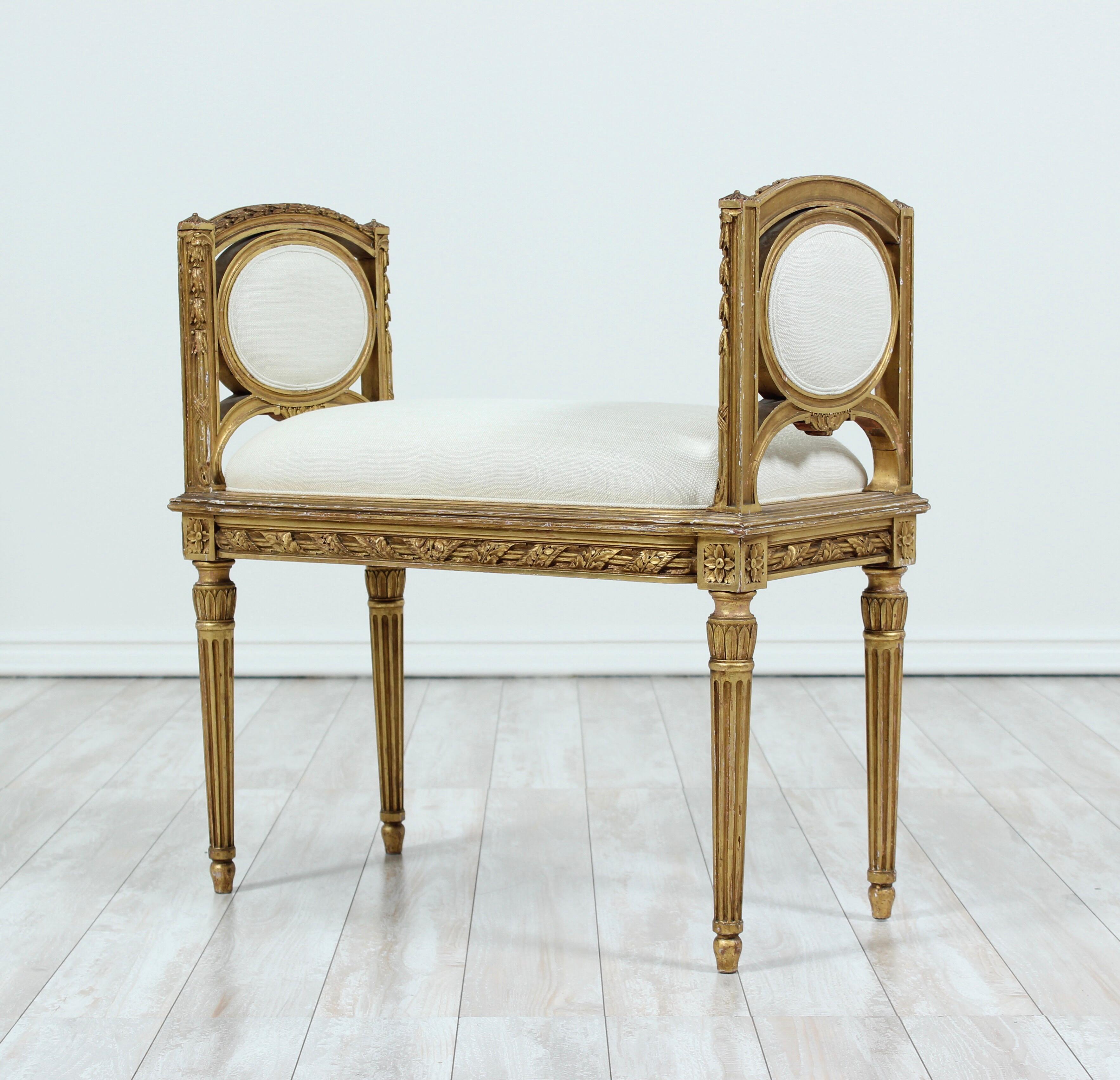 Beautiful, 1920s French Louis XVI-style carved gilt-wood bench newly upholstered in Belgian linen. 

The perfect bench for placement wherever a touch of sophisticated French flair is needed. 

This petite beauty is has been inspected by our team of