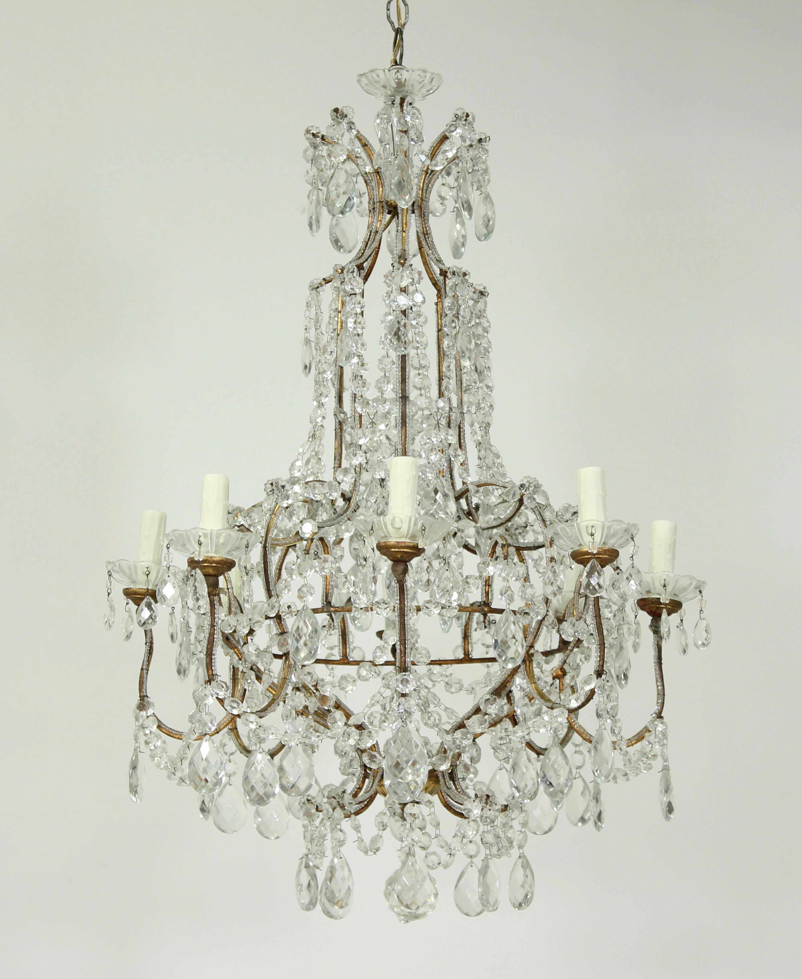 Opulent Italian 1940s chandelier consisting of a gilt-iron crystal beaded frame, gilt wood accents, faceted crystal bead garlands and prisms. The gilded frame has acquired a natural time worn patina including minor gilt loss and oxidation . This