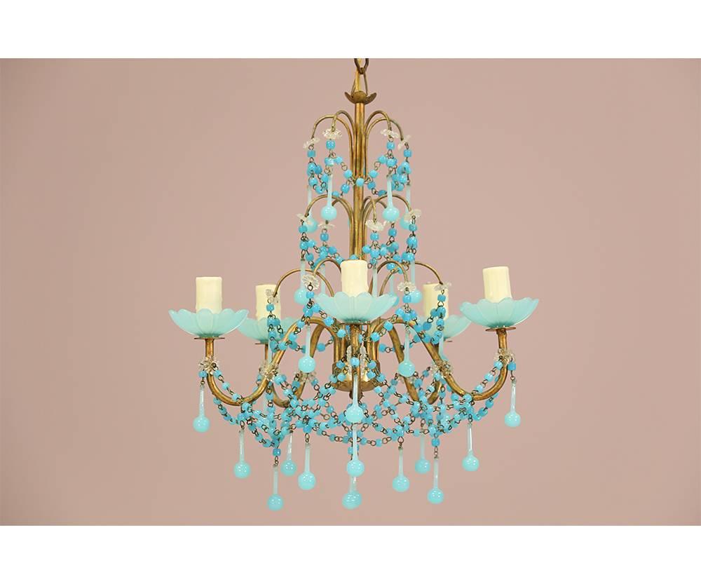 Exquisite pair of Italian 1940s petite-scale gilt iron chandeliers decorated with delicate blue opaline glass bobeches, drops and bead swags. Newly rewired. New bee wax candle sleeves. Each chandelier requires five candelabra bulbs. Original ceiling