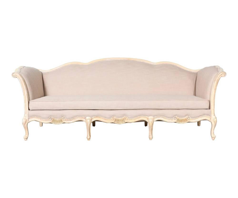 Charming,  1940s French Provincial-style sofa with a distressed paint finish, decorative carvings and new linen upholstery. Loose seat cushion.
