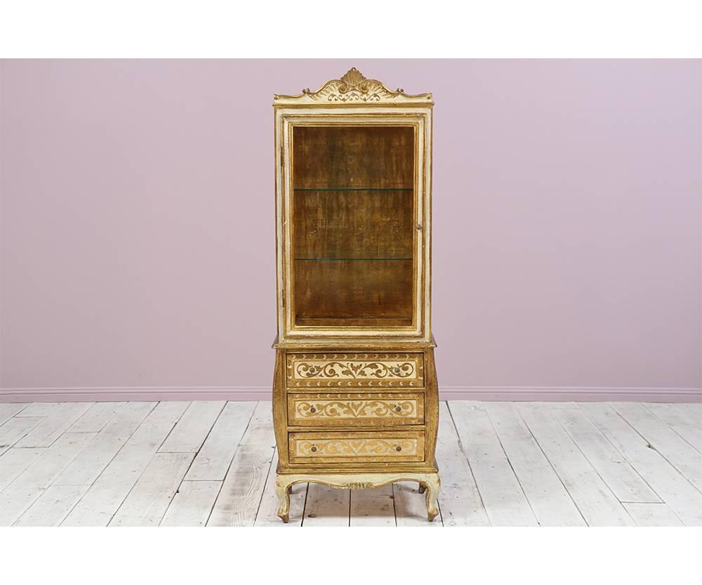 Italian, Florentine 1960s vitrine featuring a glass encasement for display purposes and three ample drawers for storage. The gilt finish is naturally distressed.