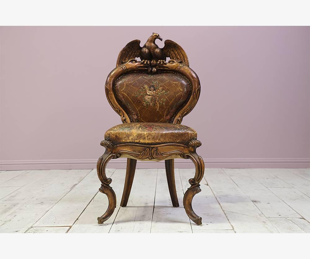 Fantastical, 19th century Italian antique carved wood side chair with a backrest depicting an eagle mounted atop the heads of two snakes and dolphins for feet. The original hand painted leather upholstery is worn and slightly torn. 