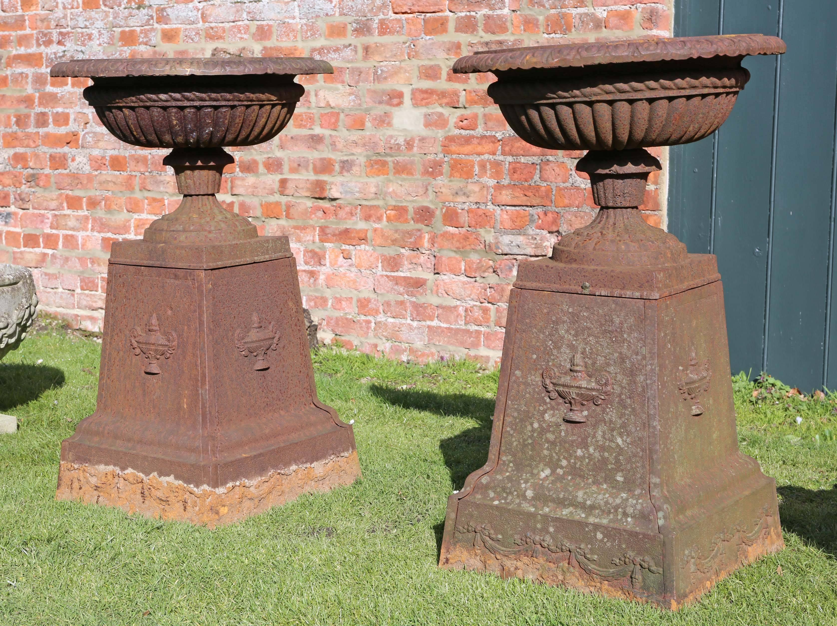 Large antique pair of Victorian cast iron planters or urns on plinths.
We believe that these date from the late 19th or early 20th century.

Nice ageing and weathering. Great style, a bit special.

Large heavy impressive pieces. Each separates