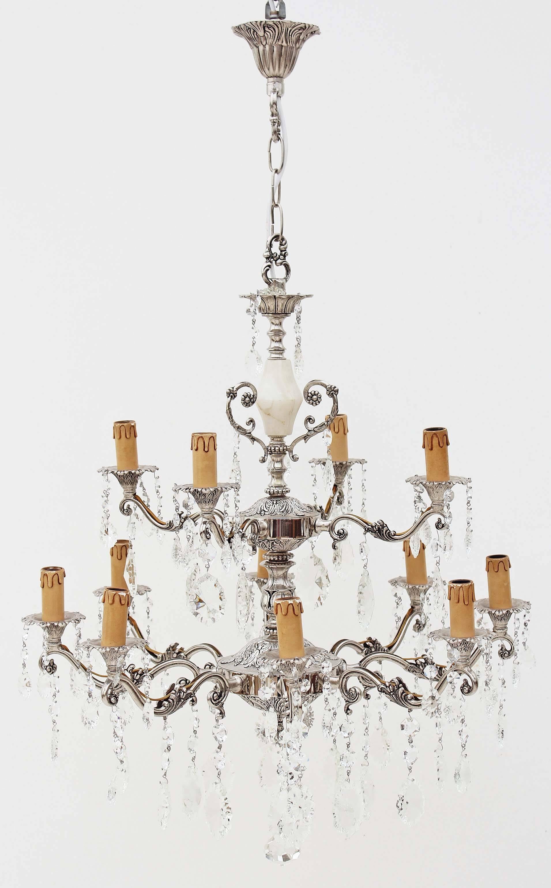 Antique twelve-lamp silver on brass and crystal chandelier.

This chandelier has a patinated silver finish on brass and other metals.

With a nice age and patina, circa 1930.

Very elegant, with a quality feel.

There is a piece of turned