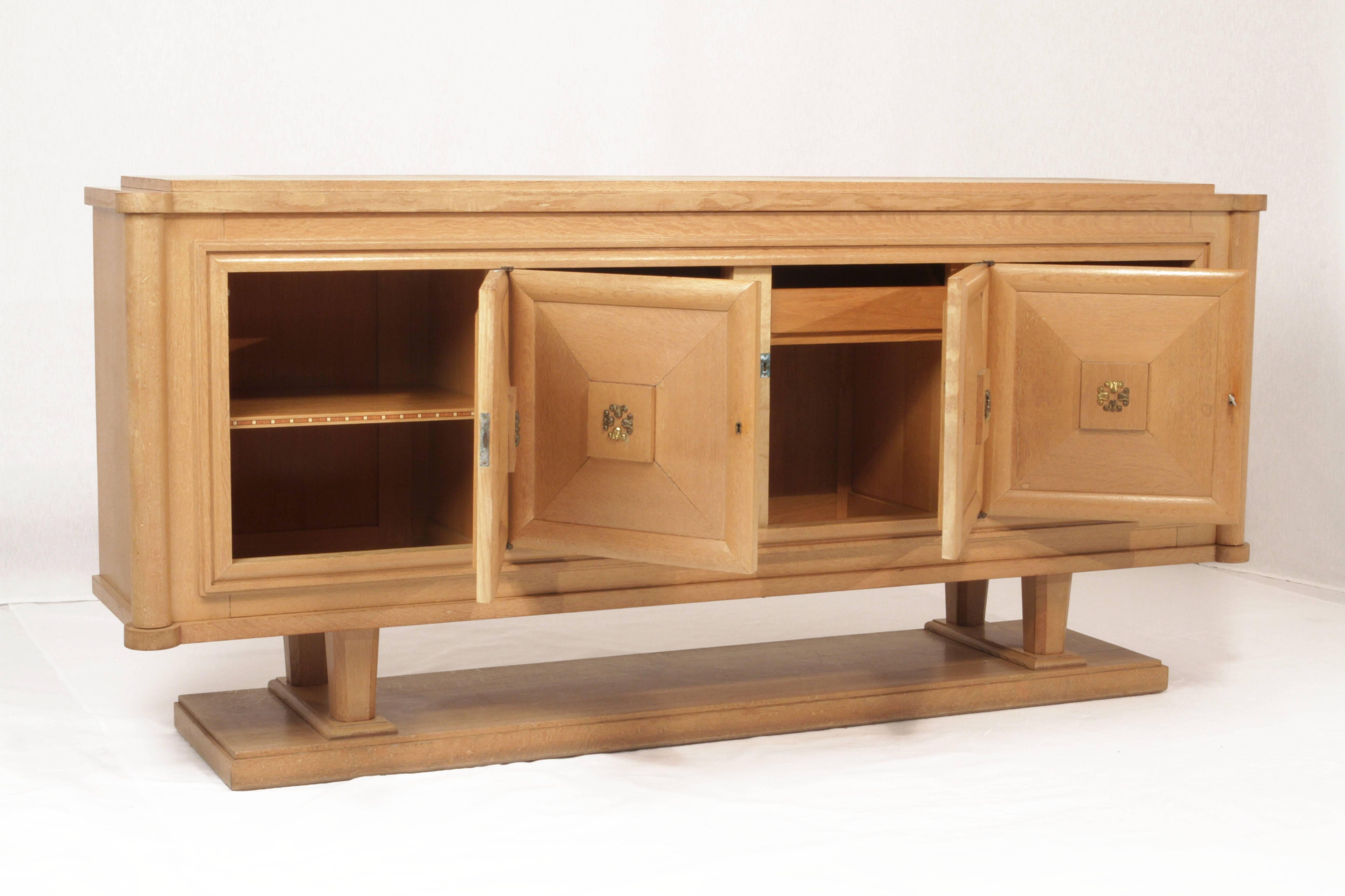 Beautiful Art Deco sideboard buffet by Gaston Poisson produced in the 1940s in light oak. For a luxurious touch, it features four doors locks with bronze ornaments and shelves with inlaid marquetry work inside and perfects the glamour of simplified