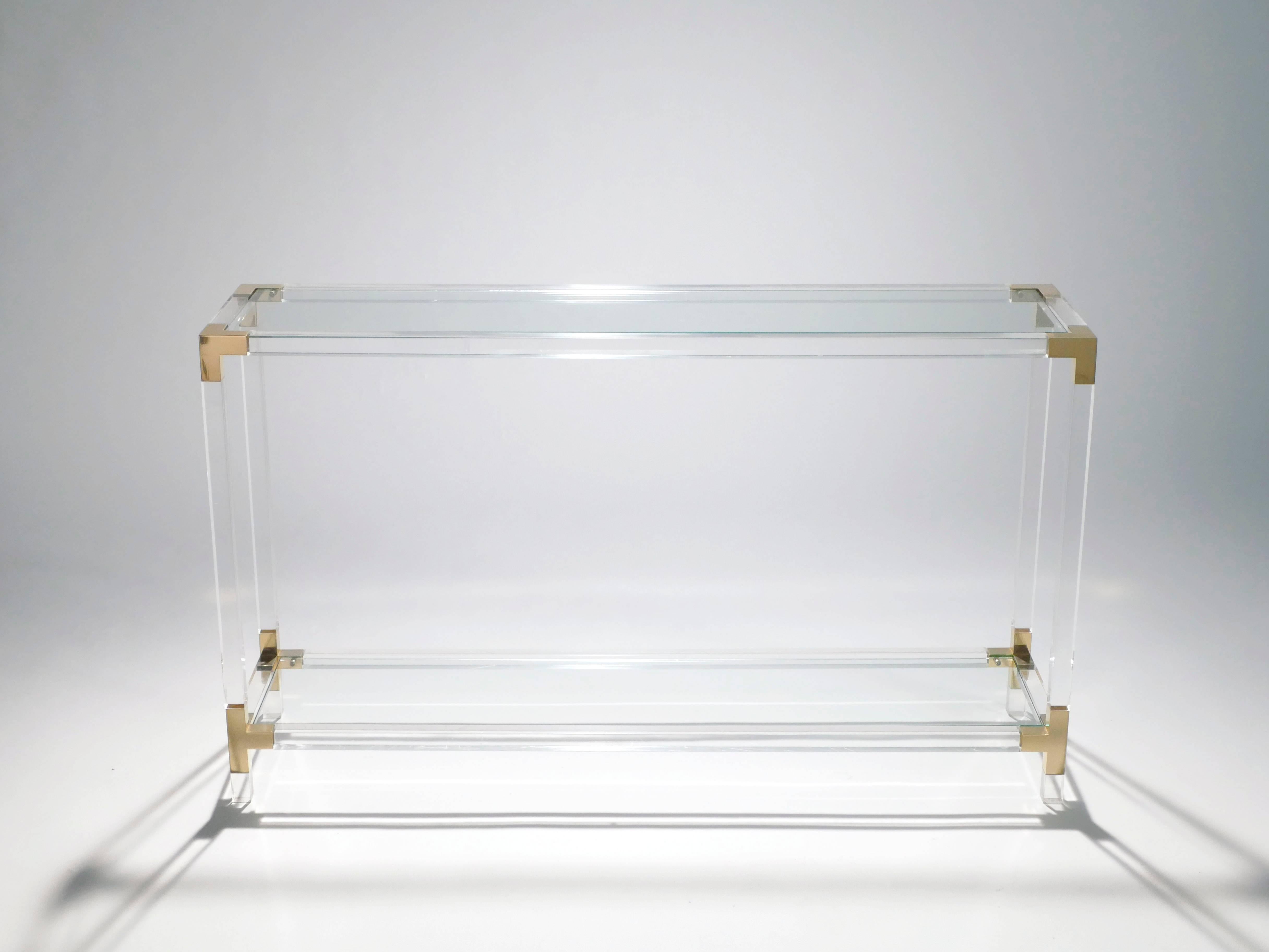 Infuse your space with a cool levity with this transparent console table, built almost entirely from plexiglass and glass. Its quality brass accents feel luxurious, while the rest of the piece gently reflects light. This Maison Jansen piece is a