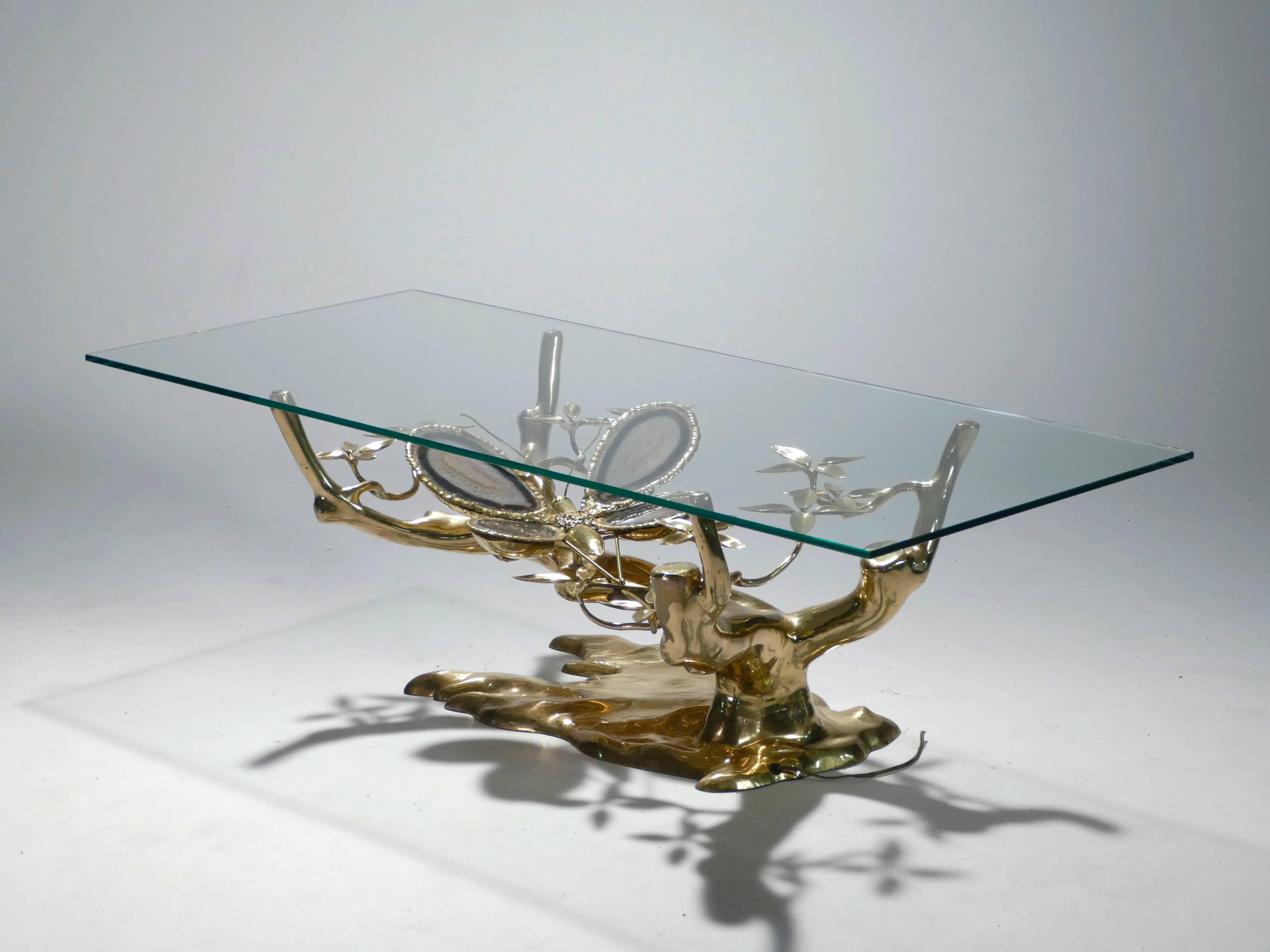 Looking directly down at this coffee table, you peer through the sharp, transparent glass to a butterfly brandishing its fascinating, agate stone wings among leaves and branches made of molten brass. This rare, extraordinary piece was designed by