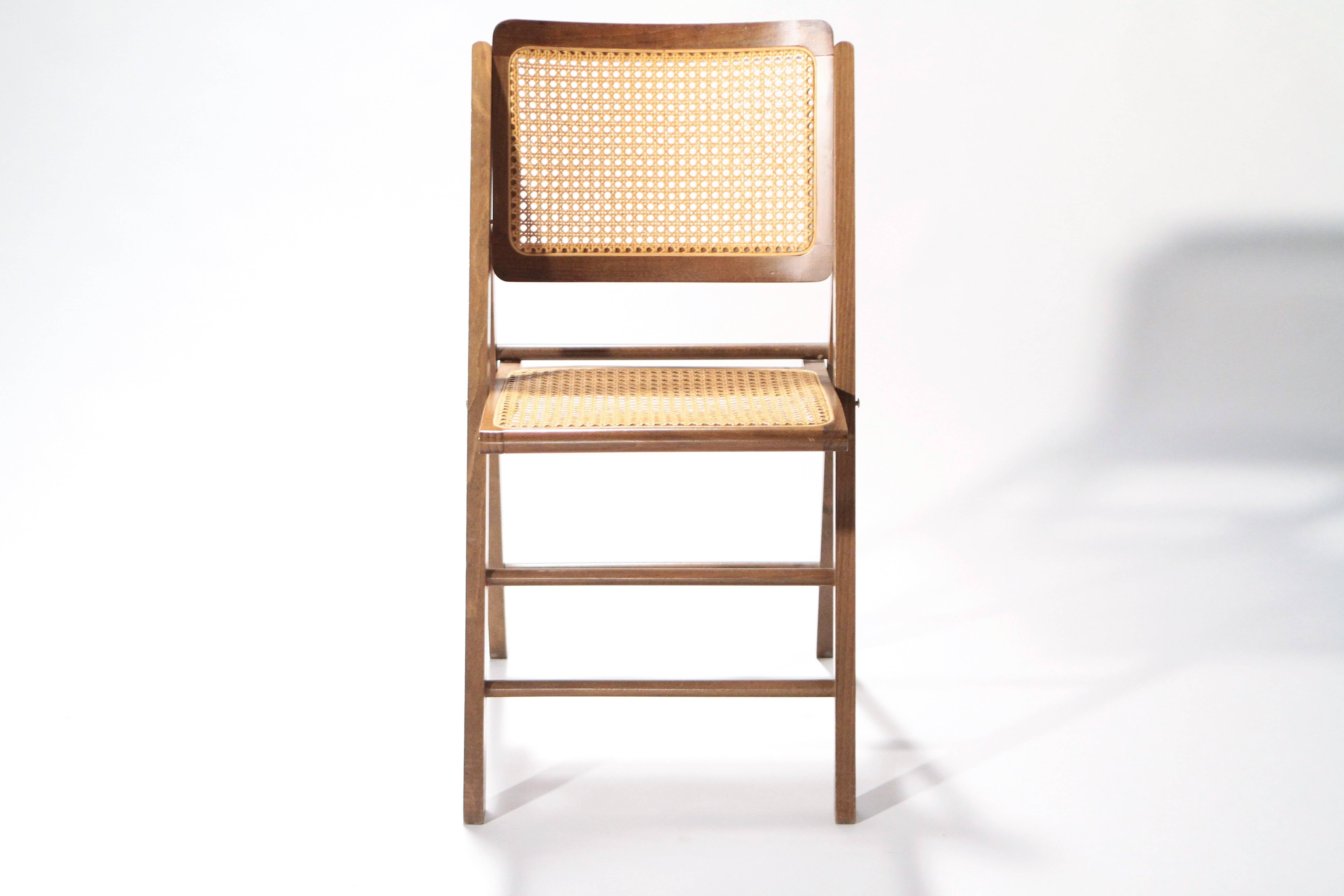The simplicity of French modernism is evident in this set of caned folding chairs from the 1950s. Constructed with warm teak wood, the chairs were designed in a creative, Minimalist style inspired by the work of Pierre Jeanneret and Gérard