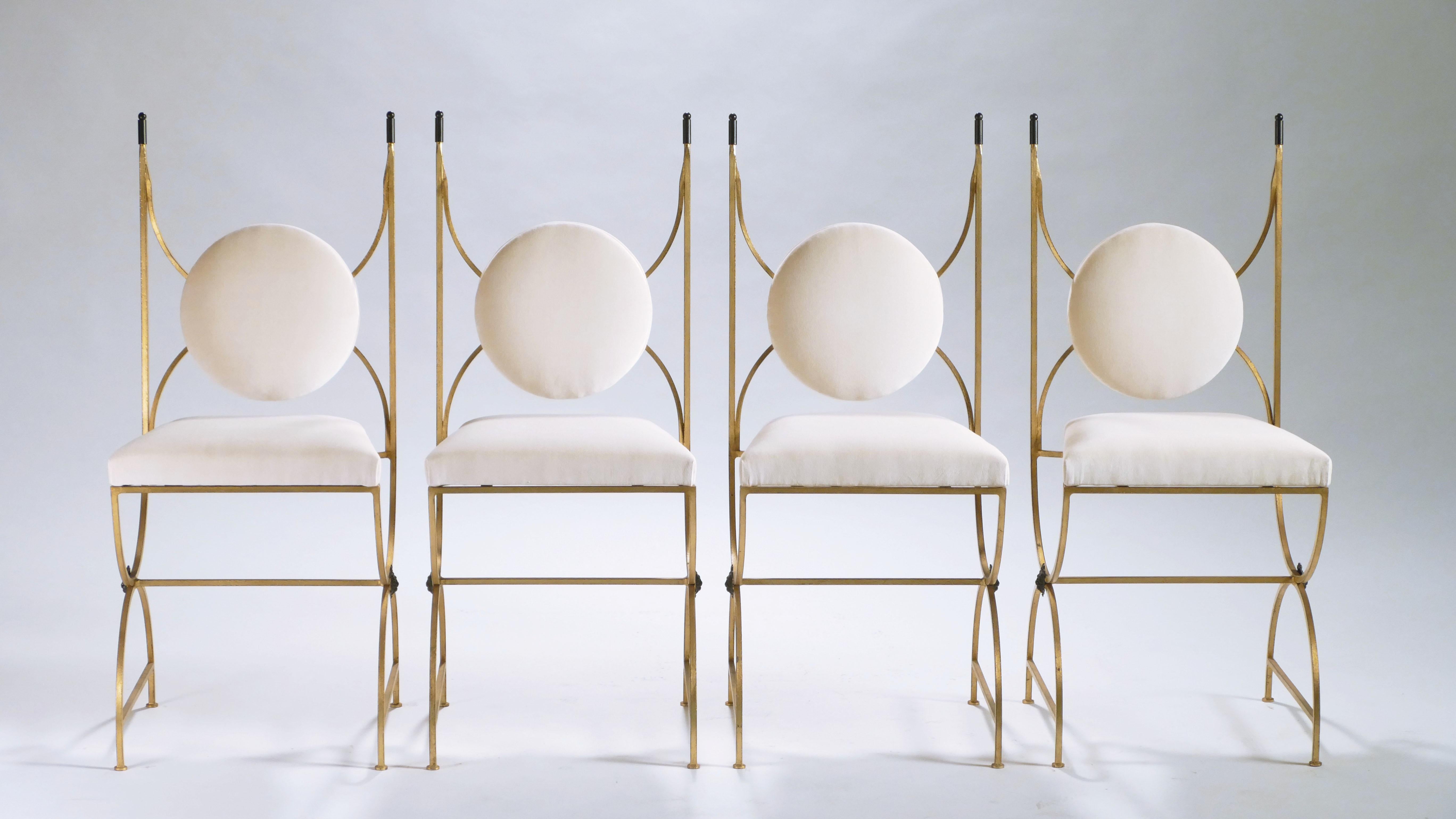 Grace your home with the true elegance of these four dining chairs. Wrought iron has been gilded with gold leaf for a gentle warm golden patina throughout the entire structure. These chairs are newly upholstered in a quality creme velvet that adds a