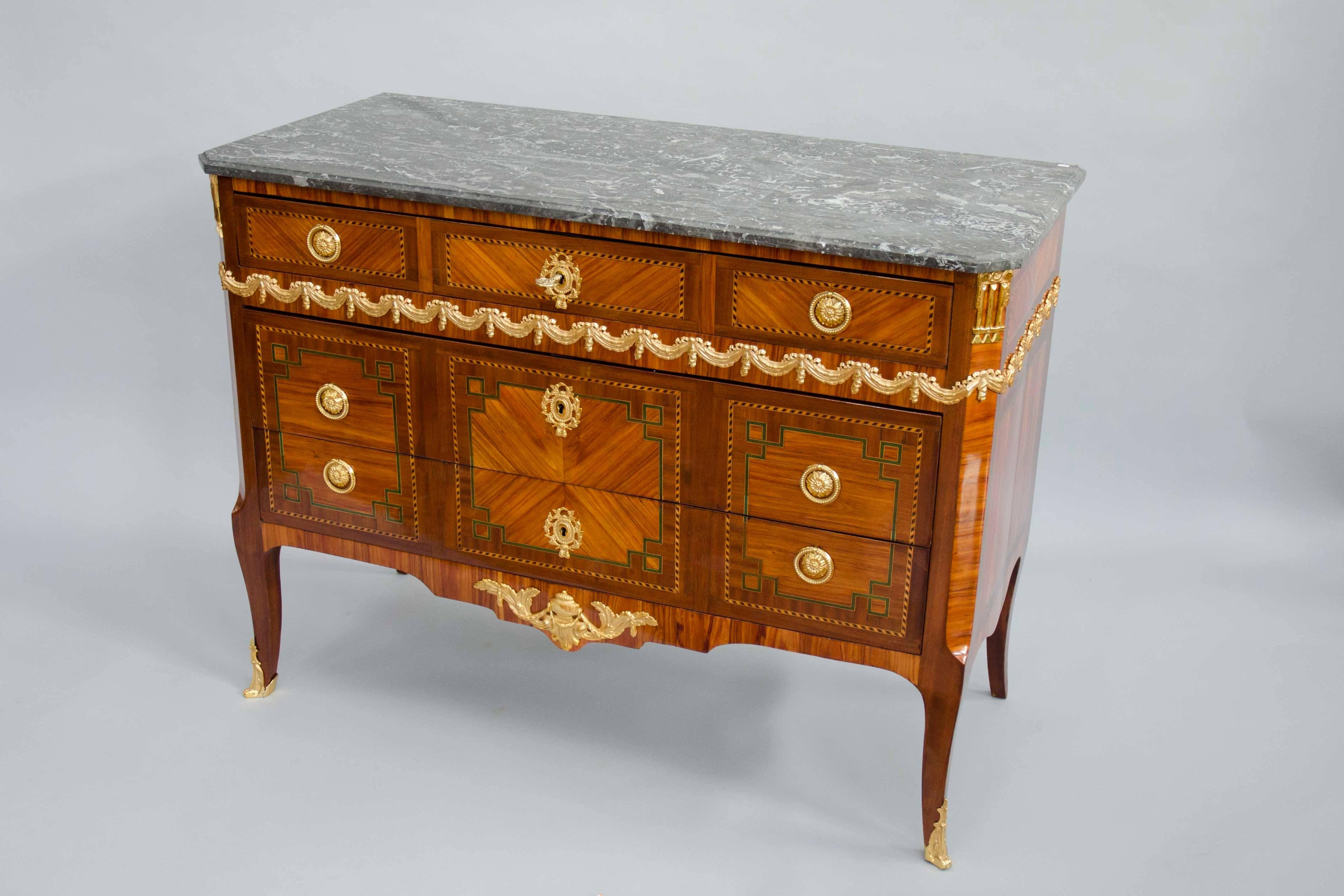 Gorgeous transition style three drawers commode. Rosewood and mahogany veneer with elegant gilt bronze decoration including a draped garland. Marble-top 