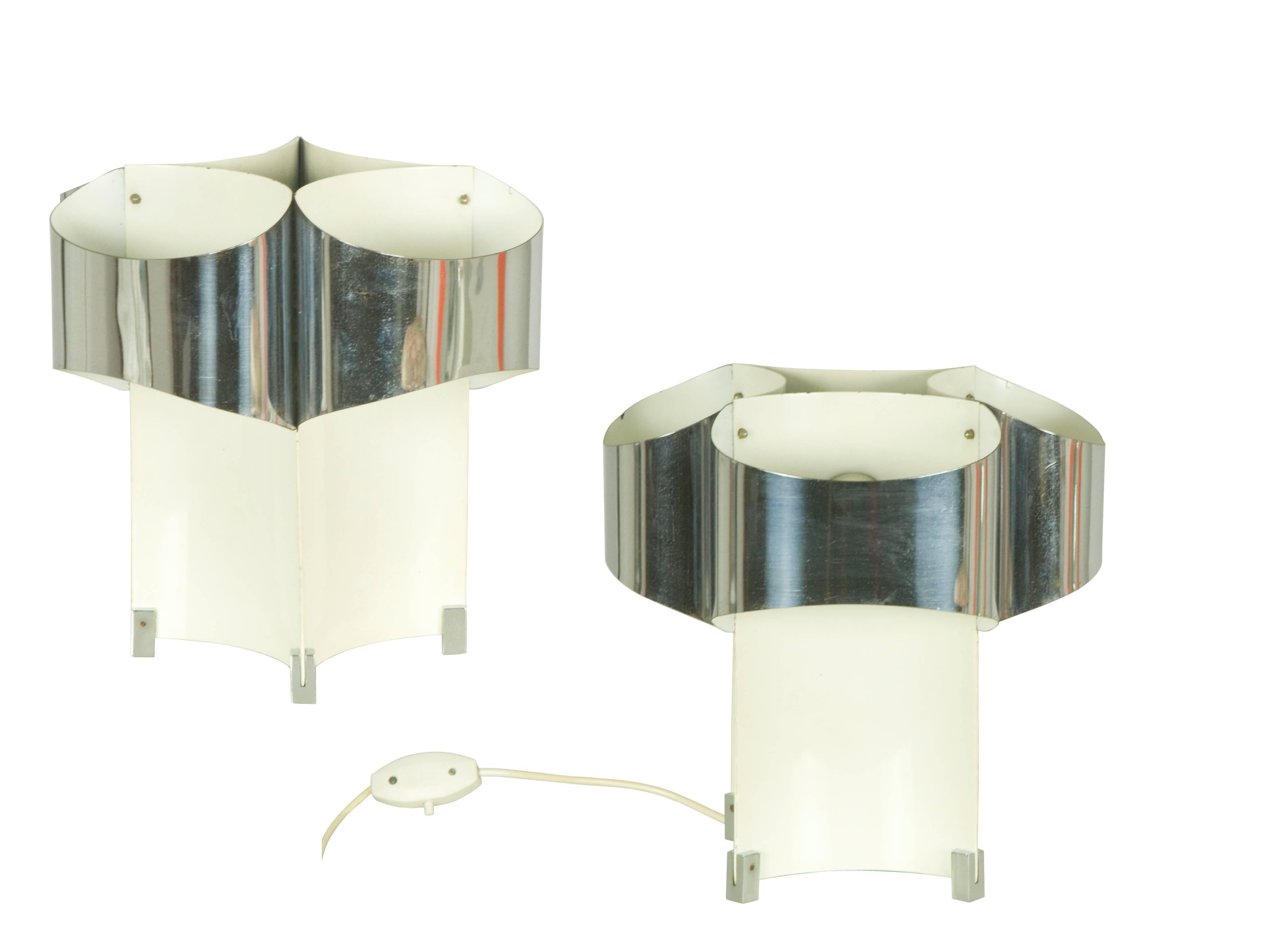 This pair of three lights table lamp was designed in Italy in the 1960s. It is made of bent chromed metal and bent painted metal; The lamps have a flat back, which makes them suitable not only as table lamps, but also to be placed on two nightstands