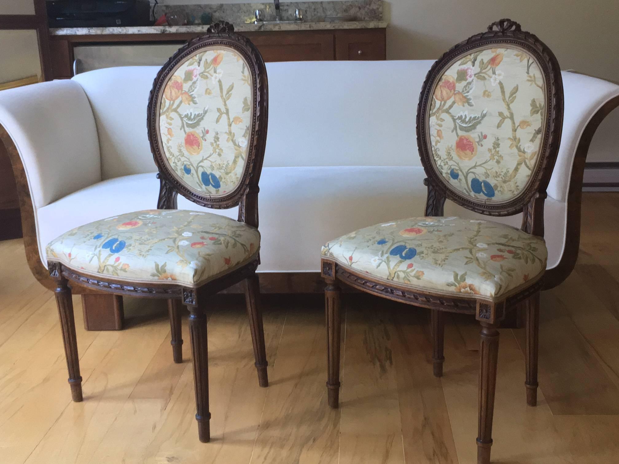 Exquisite pair of hand-carved Louis XVI style side chairs of walnut. Crest carved with ribbon ties, on fluted legs. Possibly Northern Italian, 19th century, circa 1850

Newly upholstered in a gorgeous Stark Lampas Giardino Paradiso, fruits and
