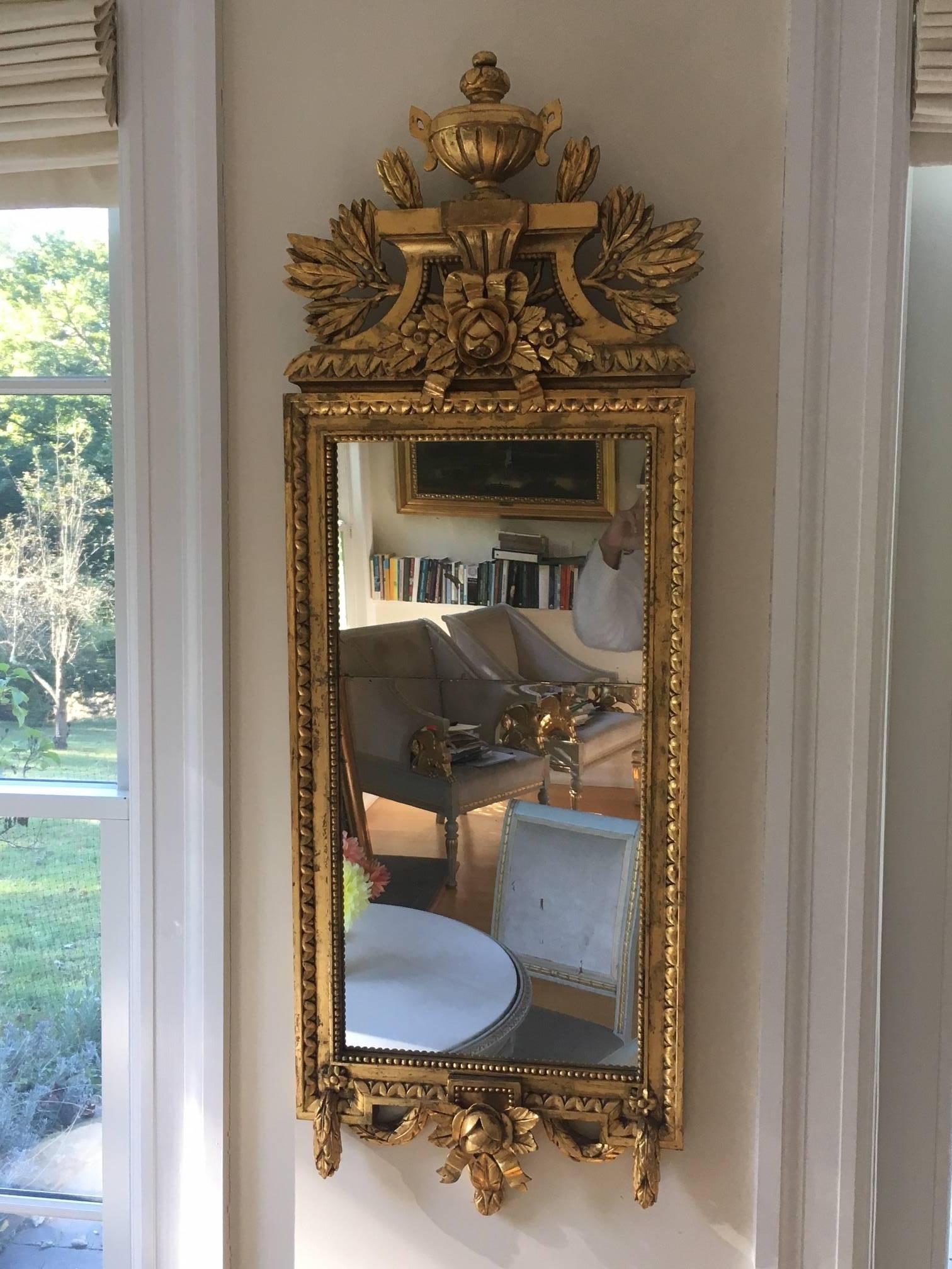 Gorgeous carved giltwood Swedish Gustavian style rectangular wall mirror circa 1880's. Lavishly decorated in the French neoclassic style with leaves, berries, urn, garlands, ribbons and roses. Mirror in two plates.

 