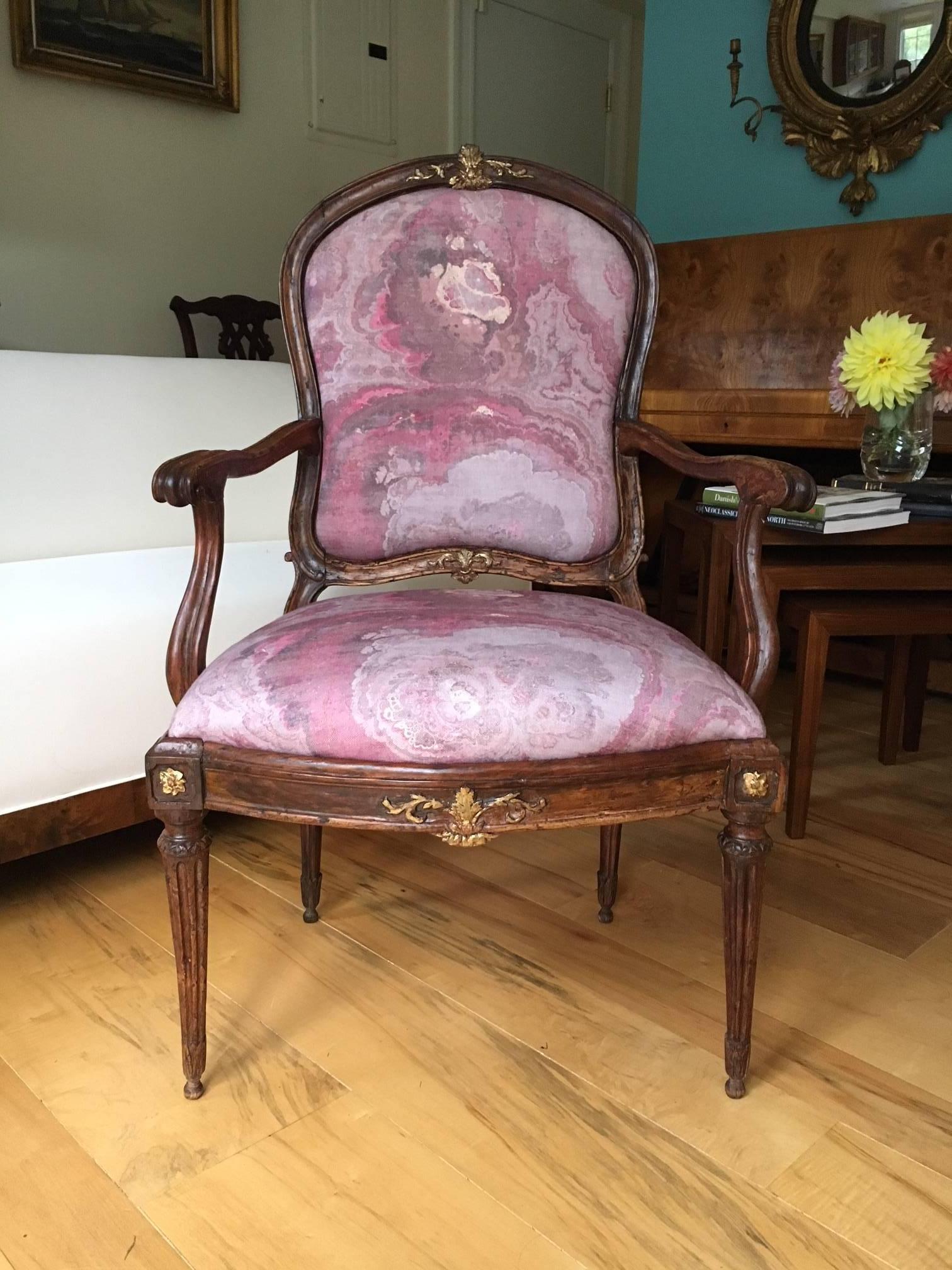 Charming parcel gilt Italian fauteuil arm chair of olive wood, of the Transition period. Originally painted, the combination of aged olive wood with the gilt accents creates a lovely blend of country charm and historical opulence. Newly upholstered